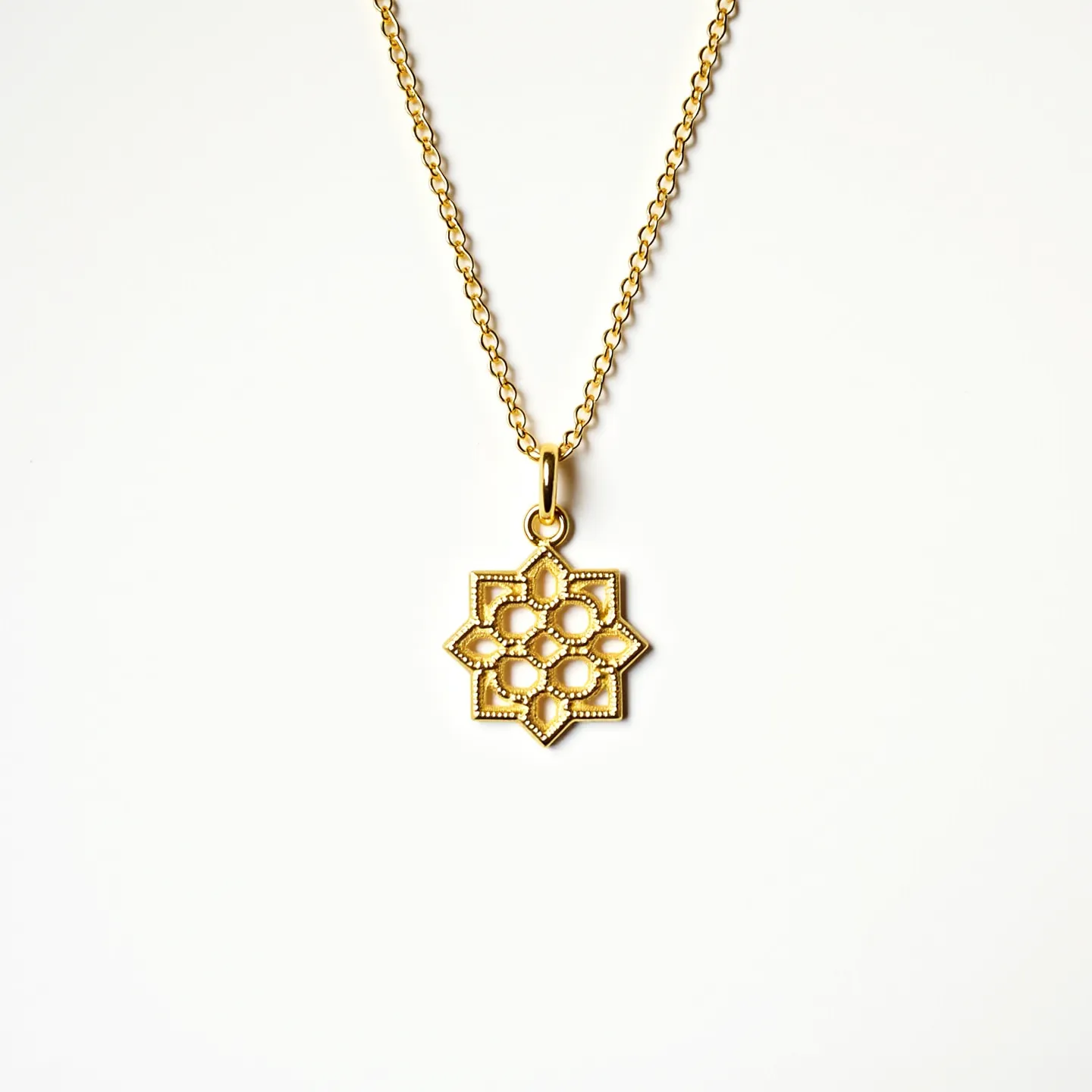 This charm necklace chain features a delicate gold-toned chain holding a geometric, star-shaped pendant. The pendant showcases a detailed, beaded texture around its edges, adding an intricate touch to the design. The central pattern includes symmetric loops that form a floral-like shape. There are no visible gems or stones set within the design. The chain appears fine yet sturdy, likely connected by a standard clasp for secure fastening.