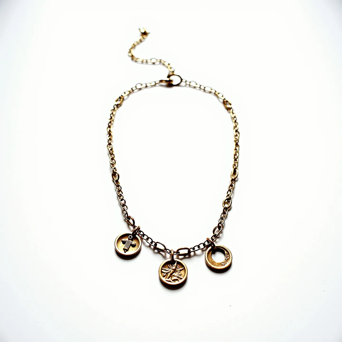 This charm necklace chain features a warm, gold-toned metal with a series of interlocking links that form its elegant structure. Suspended from the chain are three distinct charms: the first is a small circular charm adorned with a simple design, while the second charm showcases an intricate engraving of a stylized figure. The third charm is a round disc with an open center. Each charm is securely attached to the chain with a robust loop setting. The necklace is fastened with a lobster clasp, ensuring both ease of wear and security.