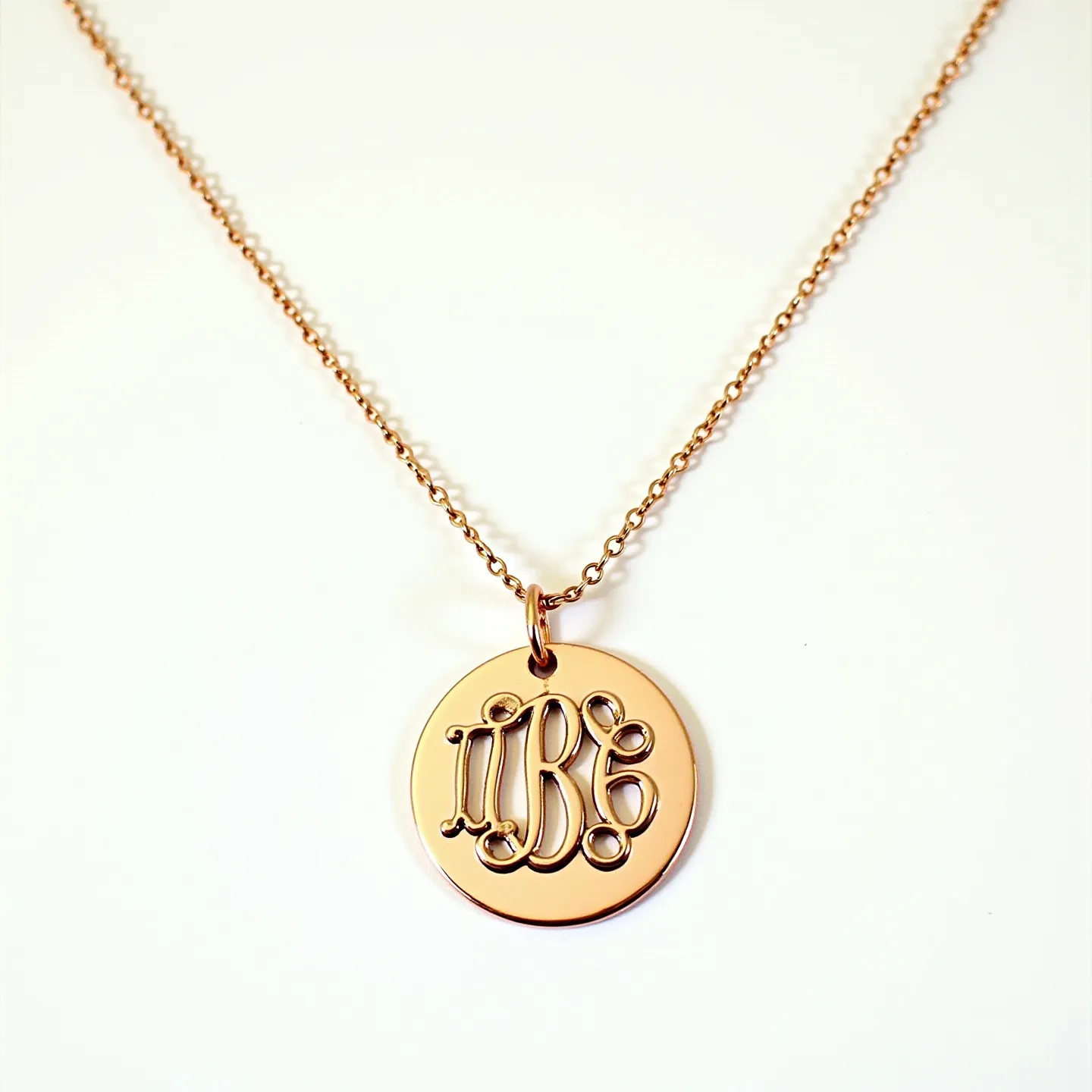 This charm necklace gold features a delicate chain crafted from gold, showcasing a beautifully polished surface. The charm is a round pendant with intricate monogram detailing in a cut-out style, also made of gold, adding elegance to the design. It is attached to the chain with a simple gold loop that allows for smooth movement along the chain. The necklace is secured with a small, streamlined clasp that ensures both functionality and style.