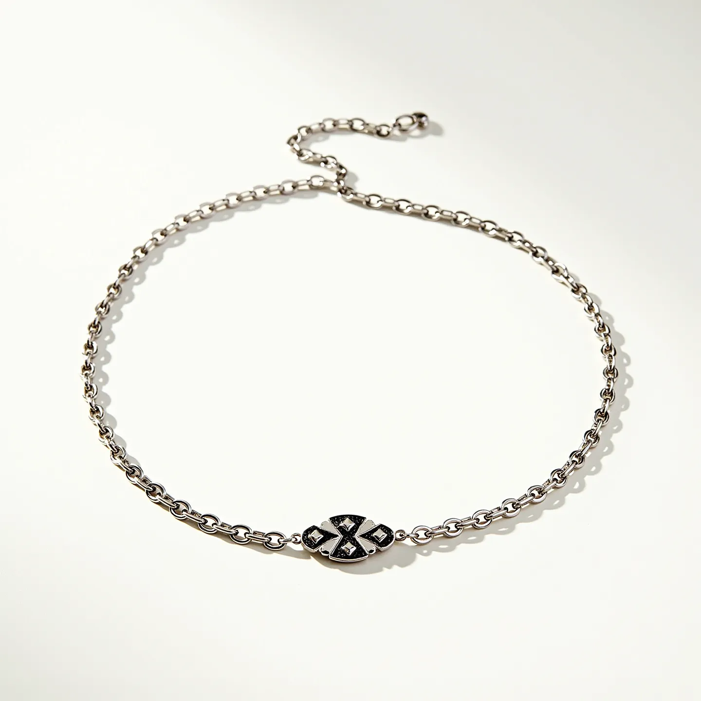 This choker chain is crafted from a polished metal, likely silver or stainless steel, featuring a series of uniform links that form a seamless and elegant circle around the neck. At its center is an ornate oval medallion, embellished with black stones set in an intricate pattern that adds depth and contrast to the piece. The stones are round-cut and securely bezel-set, ensuring durability and maintaining a sleek profile. The chain is equipped with a delicate adjustable extension and a small clasp, providing both versatility and a secure fit for the wearer.