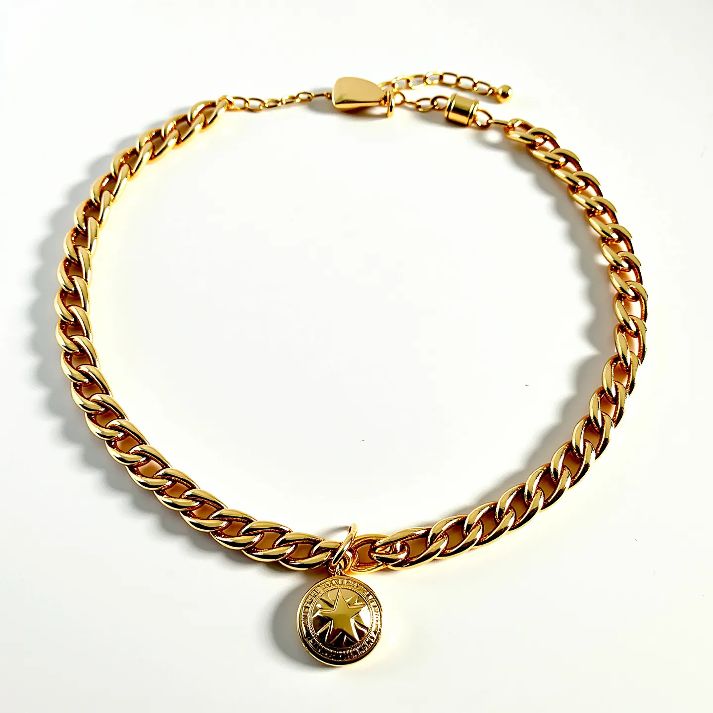 This choker chain is crafted from a polished gold-toned metal, featuring a series of interlinked curb-style links that exhibit a sleek and contemporary design. The chain is adorned with a round pendant, which showcases an engraved star motif at its center. The pendant is elegantly attached to the chain through a small loop, ensuring secure placement. The choker is equipped with an adjustable extension chain and a matching clasp, allowing for a personalized fit. The craftsmanship highlights a modern and stylish appeal, suitable for various occasions.