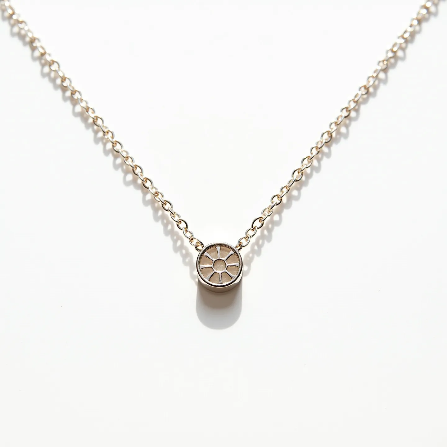 This circle necklace features a delicate chain that appears to be crafted from a polished metal, likely silver or white gold. The pendant is a small circle with an intricate design resembling a sunburst or flower, carved or engraved into the surface. The pendant is attached directly to the chain, giving it a seamless and minimalist design. It is unclear if there are any gemstones embedded within the pendant, as the detailing resembles more of an engraved pattern than a stone setting. The necklace likely features a standard clasp at the back, typical of fine chain necklaces, for secure fastening.