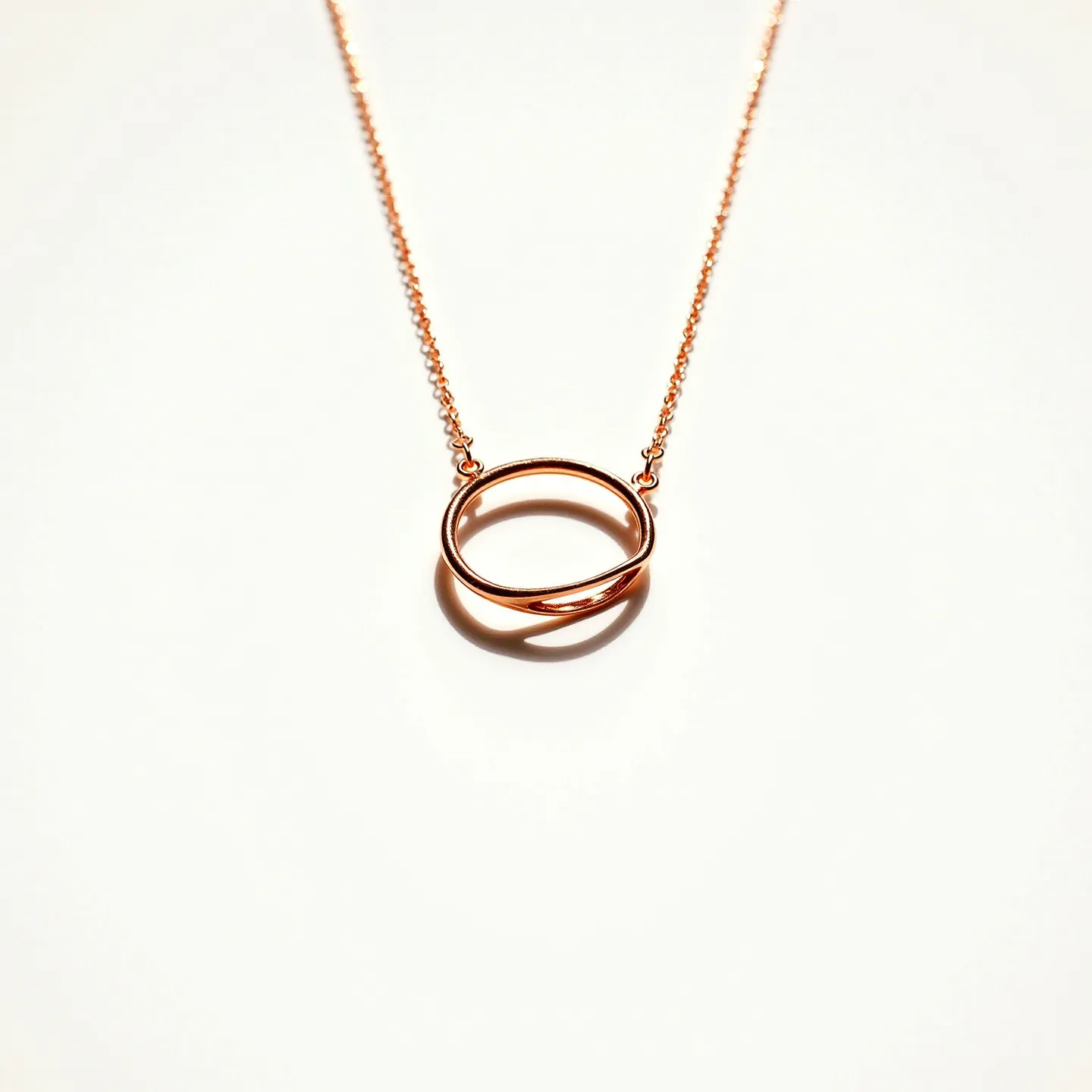 This circle necklace features a simple and elegant design, crafted from a rose gold material that gives it a warm and sophisticated appearance. The centerpiece is a looped circle or an infinity-style design, which adds a touch of modernity to the piece. The circle is attached to a delicate chain, also made of rose gold, which complements the overall minimalist aesthetic. The necklace closes with a standard clasp, ensuring security and ease of wear. Its seamless construction and glossy finish make it a versatile accessory suitable for various occasions.