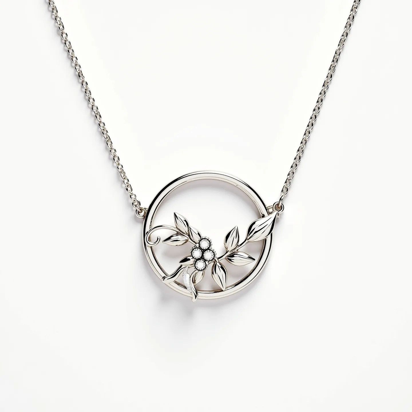 This circle necklace features a charming design with a delicate chain attached to a circular pendant. The circle is adorned with a decorative floral motif that includes a cluster of small gems, possibly diamonds or similar stones, arranged in a prong setting to form the center of the flowers. The leaves and stems are elegantly crafted, likely from a polished, silver-toned metal which enhances the sophisticated look of the piece. The chain connects seamlessly to the circle, although the specific type of clasp or attachment is not visible, contributing to the necklace's seamless and fluid design.