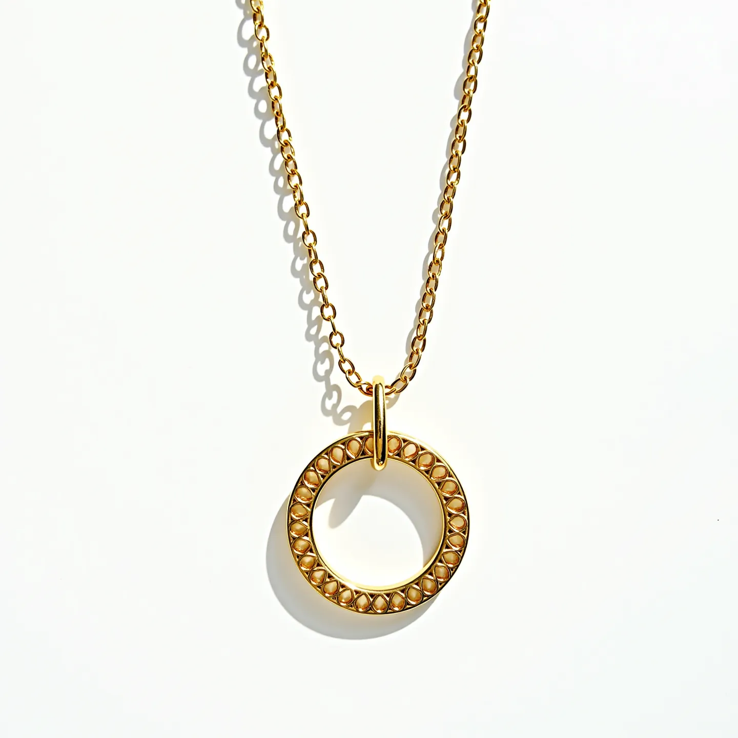 This circle necklace features a delicate gold chain with a circular pendant as its centerpiece. The pendant is crafted from a similar gold material, designed with a textured pattern that appears to consist of small, raised elements along its circumference. The simple yet elegant design does not incorporate additional gems or stones. The chain is attached to the pendant through a sturdy loop, suggesting a secure connection between the two elements. The overall aesthetic of the necklace is refined and versatile, making it suitable for various occasions.