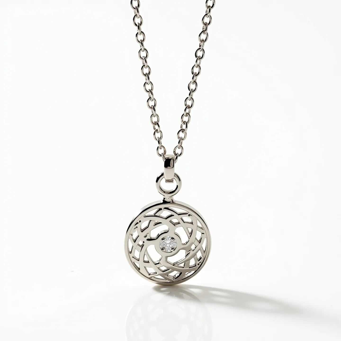 This circle necklace showcases a beautifully intricate openwork pendant made of what appears to be polished silver or a similarly lustrous metal. At the center of the pendant sits a single, round-cut gem, likely a diamond or a clear crystal, held securely in a bezel setting that enhances its sparkle. The pendant is delicately suspended from a chain composed of uniform, interlocking links, contributing to a balanced and elegant appearance. The attachment features a classic bail, ensuring the pendant hangs gracefully, while a standard clasp, likely a lobster or spring-ring type, provides secure closure for wearing. This necklace combines a modern design with timeless materials for a sophisticated accessory.