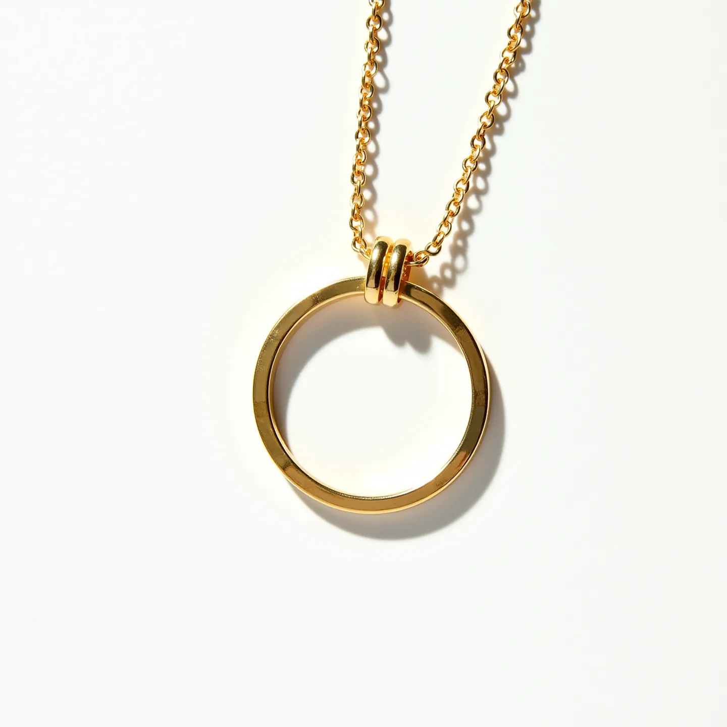 This circle necklace features a sleek, polished gold circle pendant, giving it a simple yet elegant appearance. The pendant is suspended on a gold chain that appears to be made of closely linked, delicate oval rings, enhancing its refined look. The circle pendant is held in place by two small gold grommets, adding a subtle detail to the design. The necklace is likely made from a gold-toned metal, offering durability and shine. The chain seems to have a traditional clasp at the end, ensuring secure wear. This minimalist piece is versatile, ideal for both everyday wear and special occasions, offering a classic touch to any outfit.