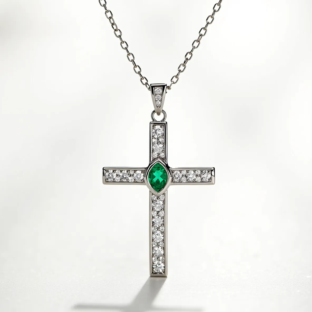 This cross diamond necklace features a striking design with a central emerald gemstone in a marquise cut set in the middle of the cross. Surrounding the emerald, the pendant is adorned with numerous small round-cut diamonds, each securely set in a pave setting, enhancing the overall sparkle of the piece. The cross is crafted from a polished metal, possibly white gold or platinum, which complements the brilliance of the diamonds and the vivid green of the emerald. The necklace is attached to a delicate chain with small uniform links, and it uses a standard bail for easy attachment to the chain, ensuring both functionality and elegance in its design.