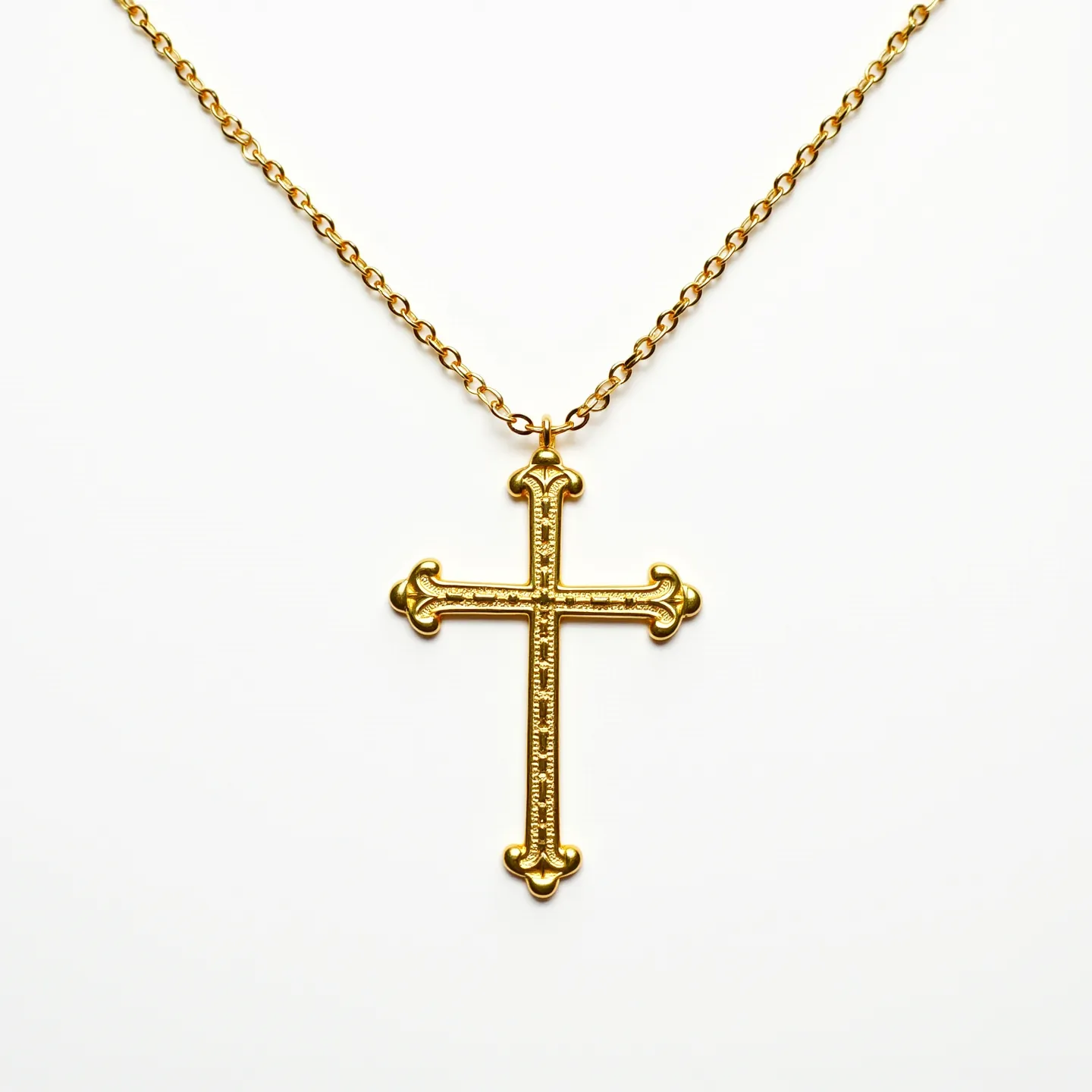 This cross necklace features a detailed and ornate cross made of gold-colored metal, showcasing intricate designs along its surface. The craftsmanship presents a textured pattern that adds depth to the cross, culminating in elegant fleur-de-lis details at each end. It is suspended from a matching gold tone chain with uniform links, providing both durability and a classic aesthetic. The necklace is equipped with a simple loop for attachment, ensuring that the cross hangs securely. This timeless piece exhibits a blend of sophistication and traditional design.