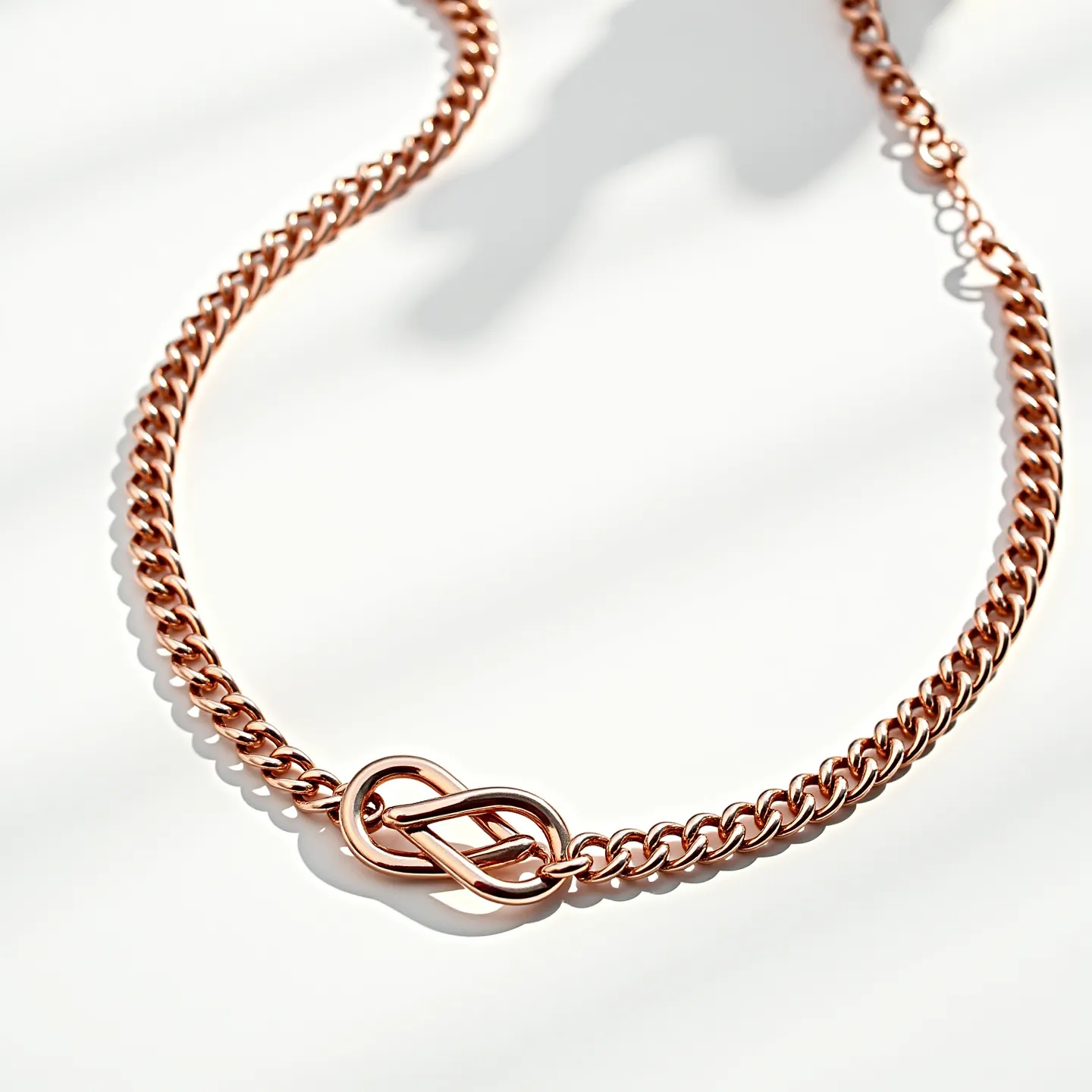 This Cuban link chain is crafted from a metal with a warm, rose-gold finish, lending it a luxurious and refined appearance. The chain features tightly interlocking links that create a smooth, continuous loop. At the center, an elegantly designed knot-like element adds a focal point and enhances the overall aesthetic. The clasp is a subtle, functional component, ensuring secure wear while maintaining the design's sleekness. The chain combines both classic style and modern flair, making it a versatile accessory for various occasions.