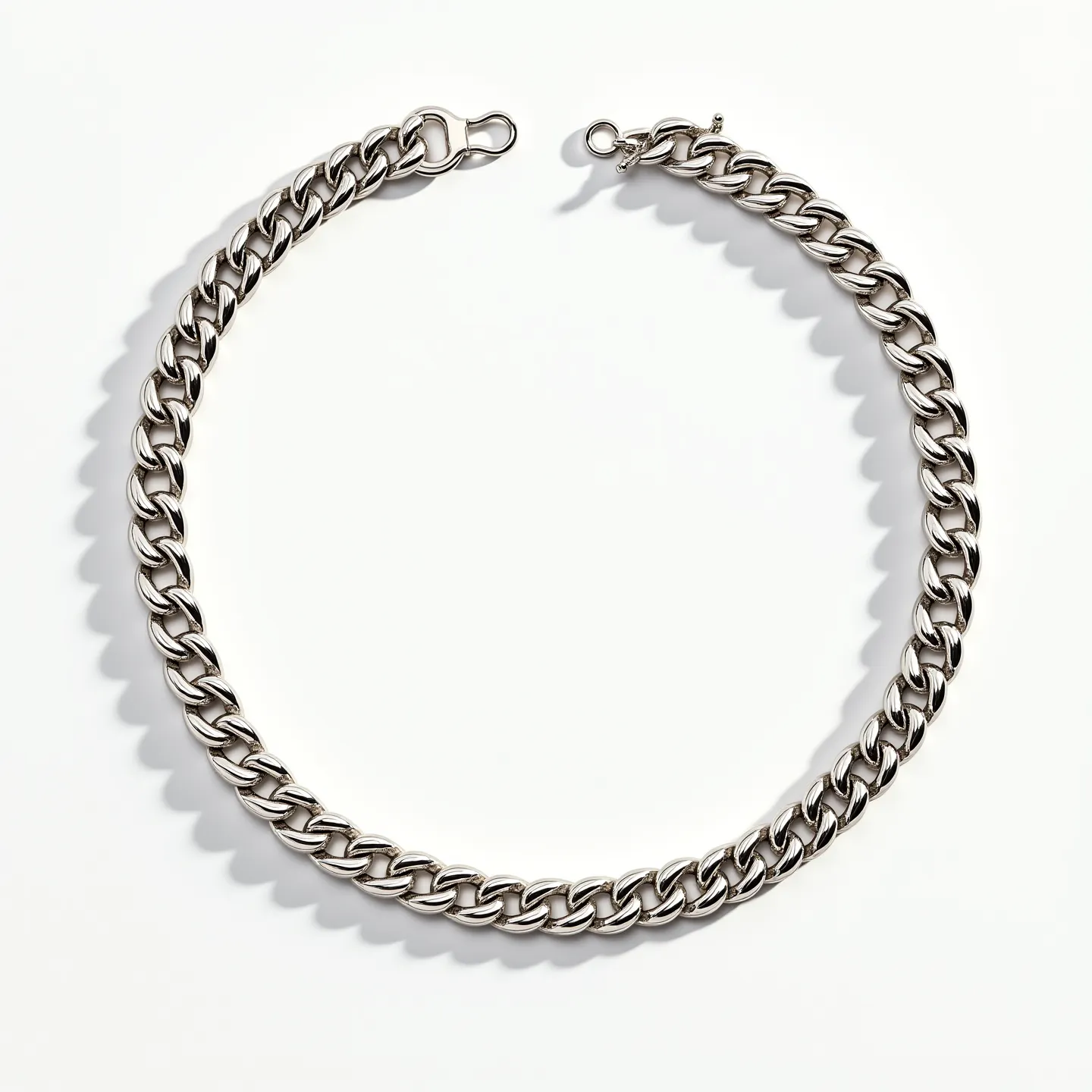 This Cuban link chain features a series of interlocking, rounded links that create a sleek and polished appearance. The material appears to be a bright, reflective metal, likely stainless steel or white gold, lending it a modern and sophisticated look. There are no visible stones or gems embedded in the design, ensuring the focus remains on the uniformity and gleam of the chain itself. The clasp is a sturdy lobster claw, providing a secure and functional attachment that complements the robust style of the chain. Overall, this chain is designed for durability and aesthetic appeal.