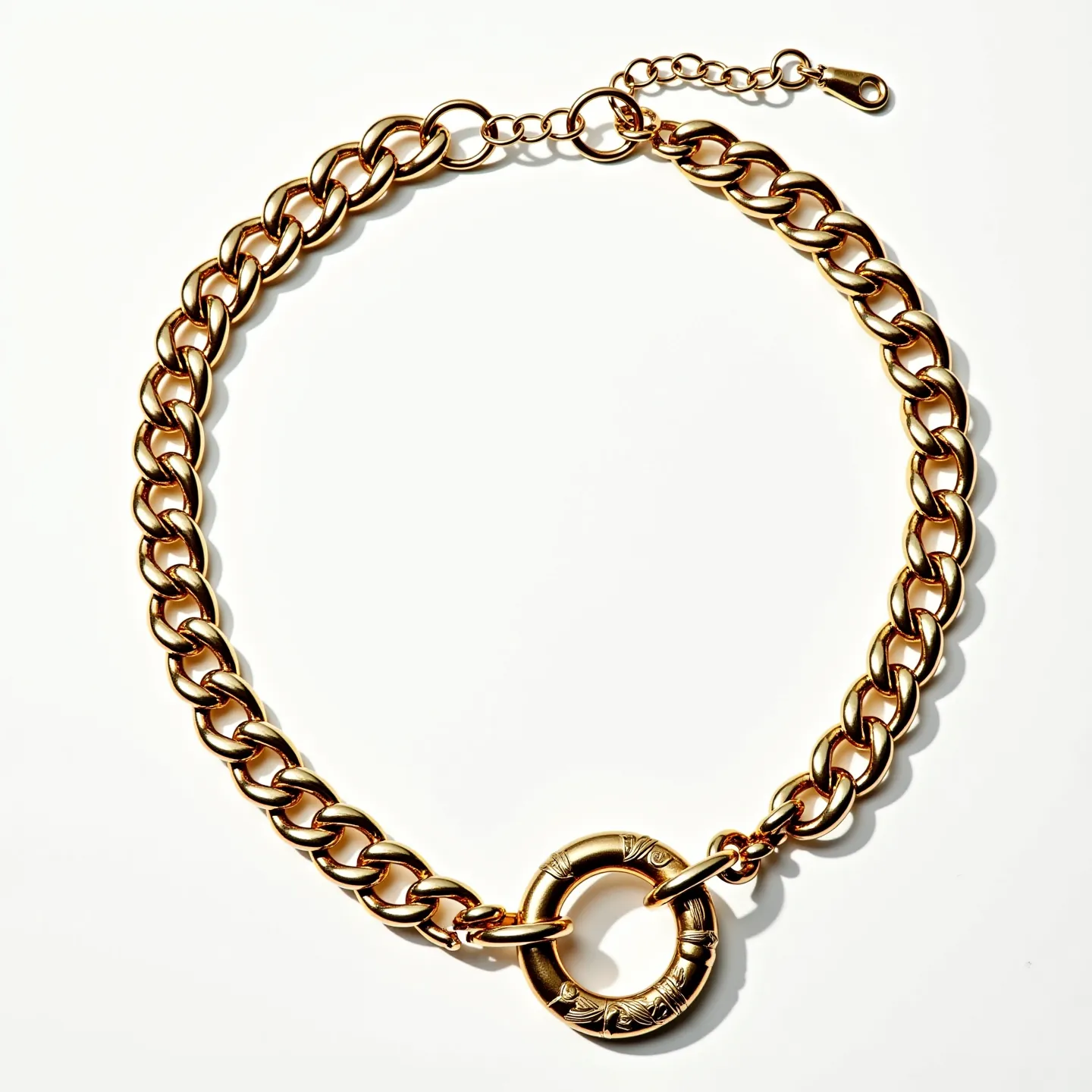 This curb chain is crafted from gold-toned metal, featuring interlocking links that create its classic, robust design. It includes a prominent circular charm with engraved detailing, adding an element of visual interest. The chain is equipped with an adjustable extension and a lobster clasp, providing versatility and secure fastening. The overall craftsmanship suggests a focus on both style and durability, making it a versatile addition to casual and formal ensembles.