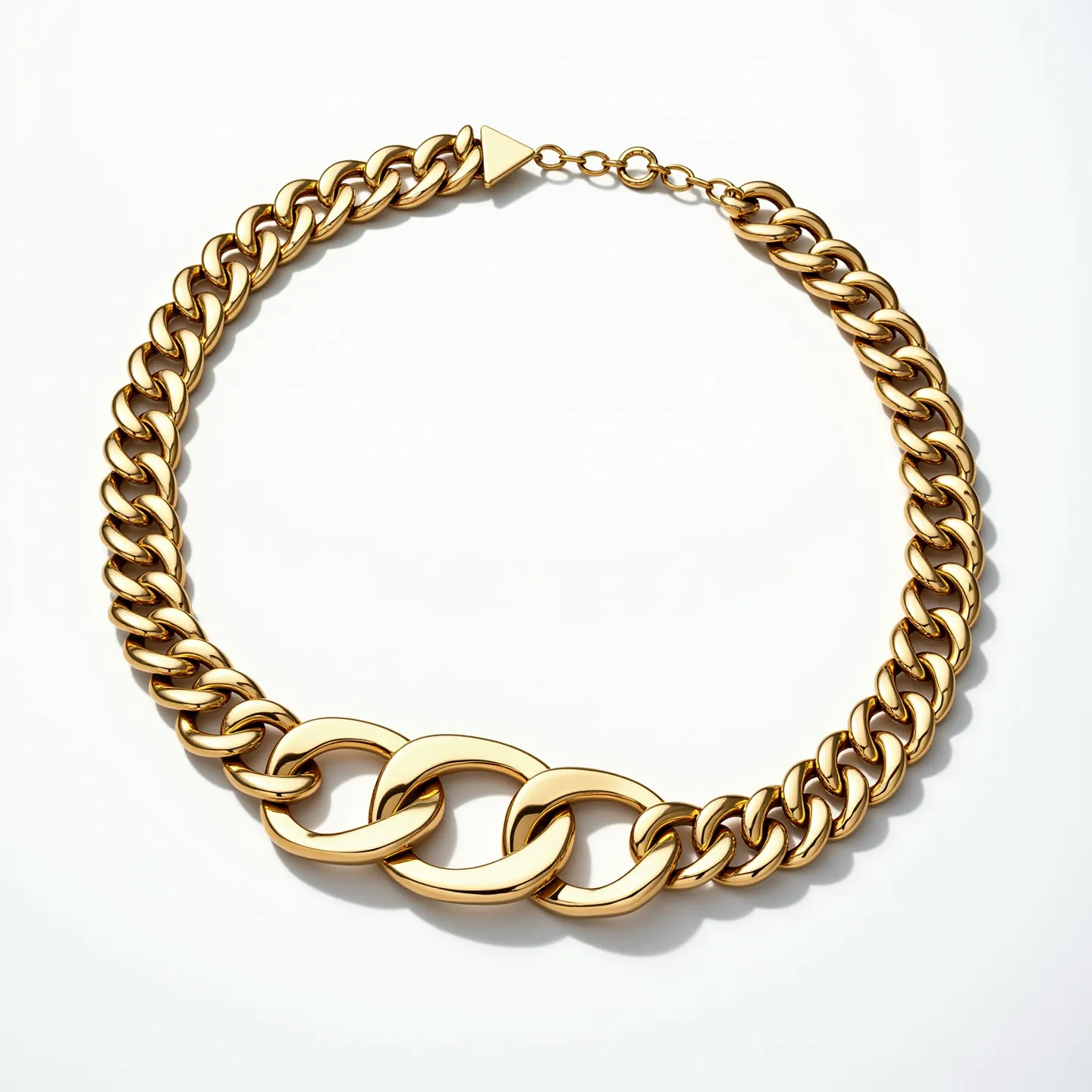 This curb chain features interlocking links made of a polished metal that resembles gold, giving it a sleek and shiny appearance. The chain has a bold design with three larger central links that stand out prominently from the rest. These links are smoothly crafted, contributing to the overall luxurious feel of the necklace. It is equipped with a triangular clasp attached to a short extension chain, ensuring a secure fit. The absence of any visible gemstones or additional adornments emphasizes the chain’s minimalist and sophisticated design, making it a versatile accessory.