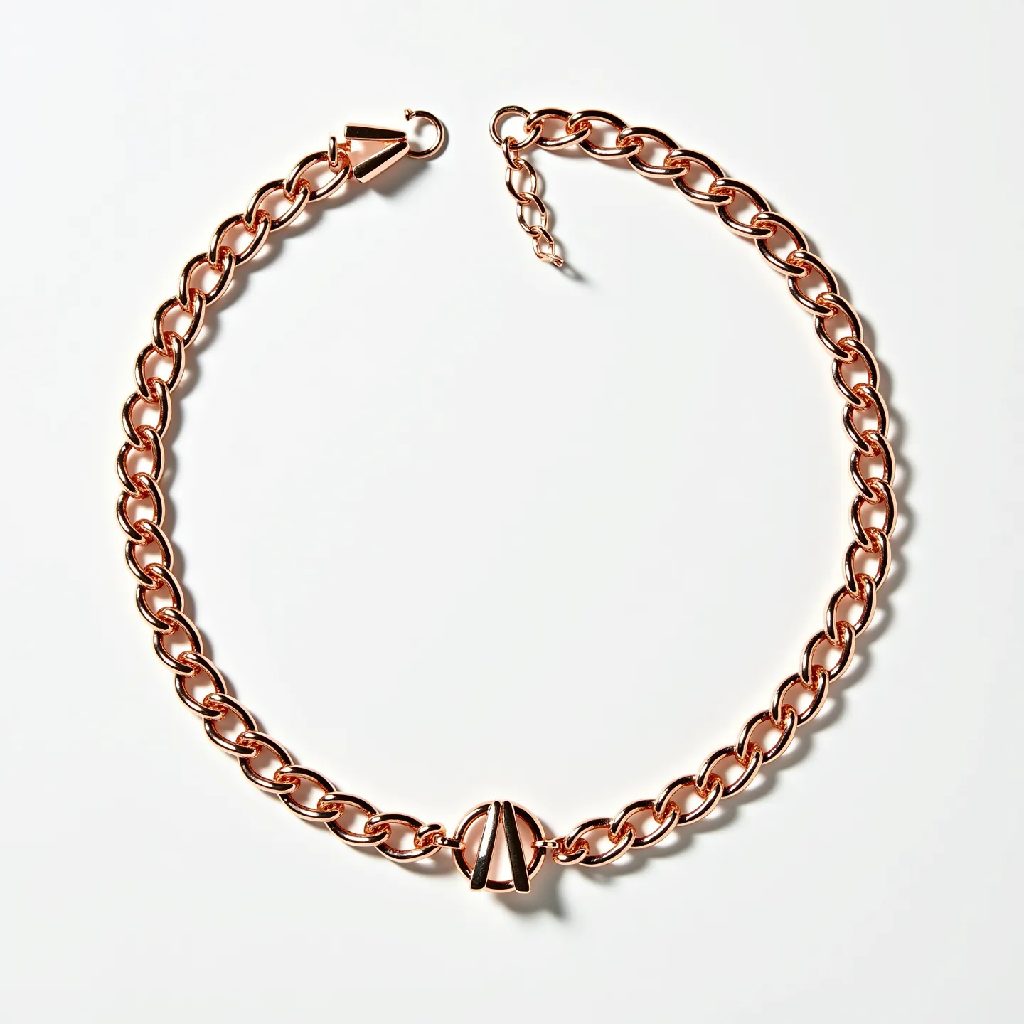 This curb chain features a series of interlocking, oval-shaped links crafted from a shiny, rose gold-toned metal. At the center, a distinctive geometric charm adds a focal element, enhancing the chain’s visual interest. The chain is equipped with a lobster claw clasp for secure fastening and adjustability. The uniformity of the links and the warm hue of the metal give the chain an elegant and sophisticated appearance.