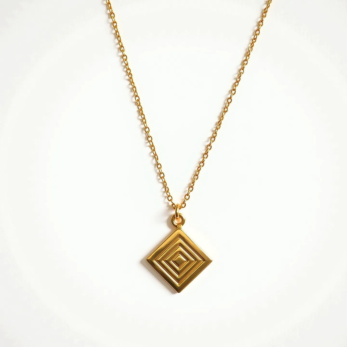 This custom charm necklace features a delicate gold chain, showcasing a geometric pendant with a diamond shape and concentric square design, adding an elegant and modern touch to the piece. The pendant is crafted from a golden metal, giving it a luminous and luxurious appearance. The necklace is fastened with a secure and stylish clasp that complements the overall look. The simplicity and sophistication of the design make it a versatile accessory suitable for both casual and formal occasions.