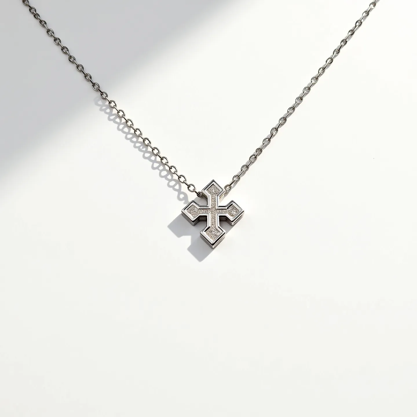 This custom charm necklace features a metal chain adorned with a cross-shaped charm, crafted in a sleek, polished silver tone. The charm is intricately designed and set with sparkling stones that appear to be round-cut and set in a pave style. The overall effect is both elegant and modern, with the stones adding a touch of subtle brilliance. The chain appears to use a standard link construction, providing durability and flexibility. A traditional clasp ensures secure and convenient fastening for the wearer.