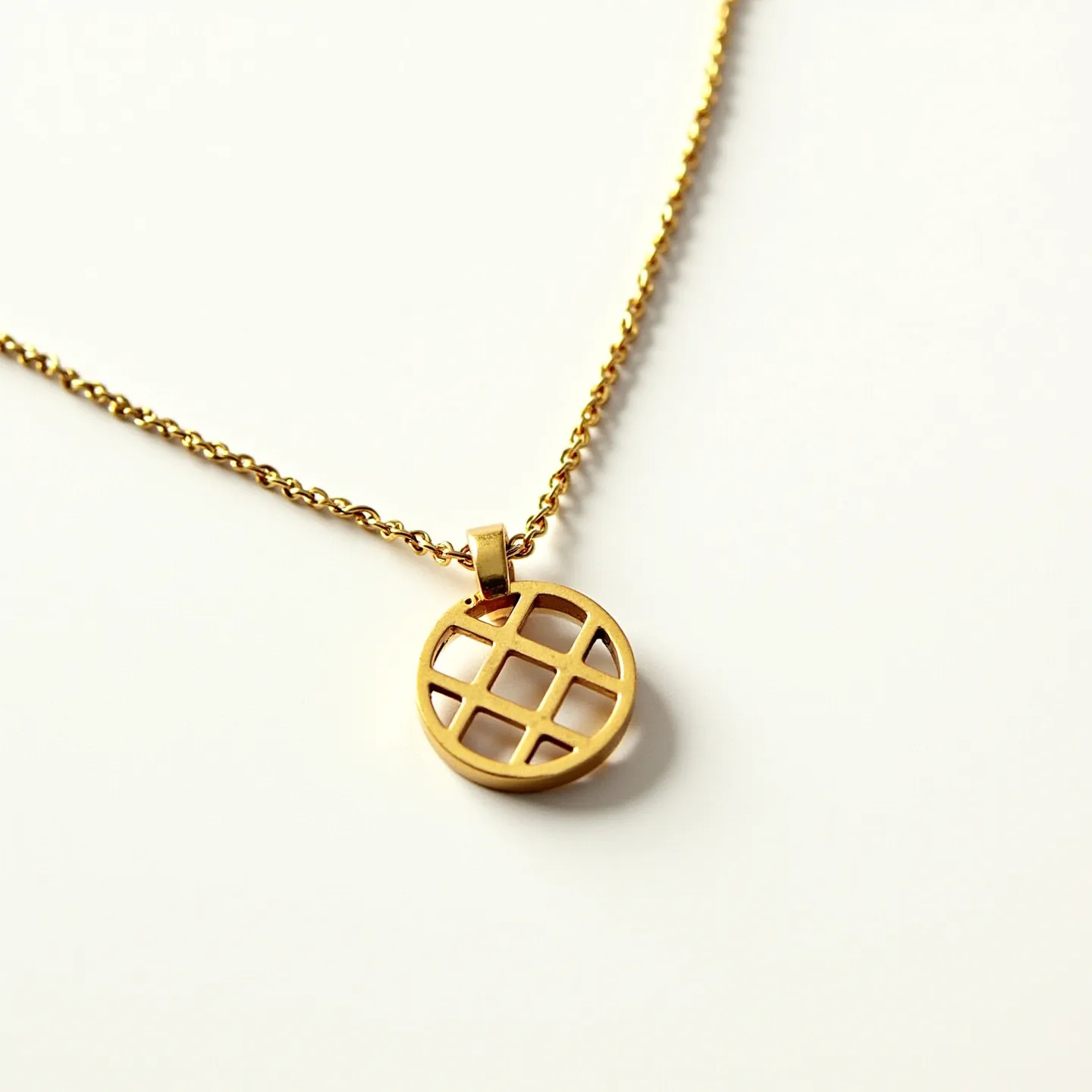 This custom charm necklace features a delicate chain crafted from a gold-toned metal, creating a sleek and modern aesthetic. The highlight of the necklace is a circular pendant with an intriguing cut-out grid pattern, providing a contemporary and artistic flair. The pendant is smoothly attached to the chain with a matching gold-toned bail, ensuring seamless integration between the elements. The overall design is minimalist yet eye-catching, making it a versatile accessory for various styles and occasions.