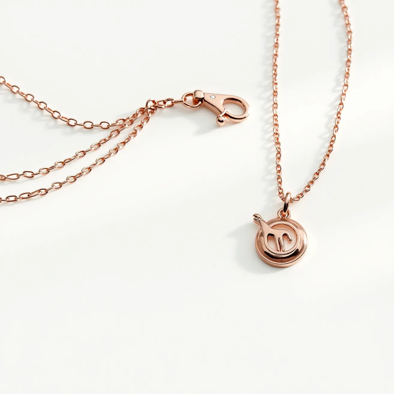 This custom charm necklace features a delicate rose gold chain, complemented by a lobster clasp for secure attachment. The charm itself is a circular pendant, crafted in the same rose gold hue, with an elegant, cut-out design at its center. This piece radiates a simple yet sophisticated style, making it versatile for various occasions while reflecting a personalized touch.