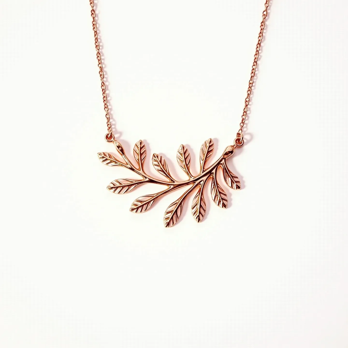 This custom necklace features a delicate chain made of what appears to be gold or a gold-toned metal, showcasing a beautifully crafted pendant in the shape of a leafy branch. The pendant has intricate detailing, with each leaf adorned with fine etchings to simulate the texture of natural foliage. The necklace's simple chain is likely connected with small looped links, offering a lightweight and elegant attachment. There are no visible gems or stones, focusing the design entirely on the artistic expression of the metalwork.