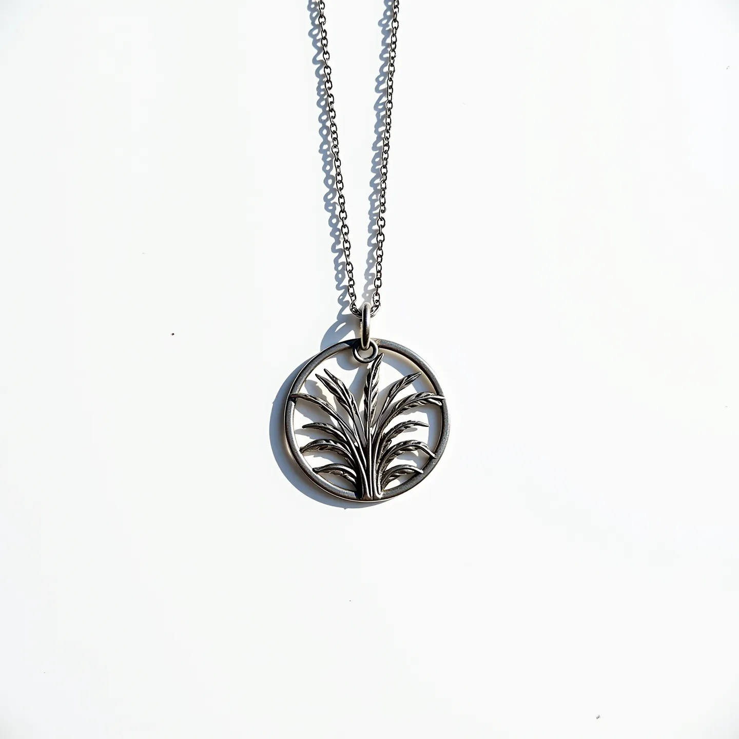 This custom necklace features a delicate and intricate circular pendant with a stylized botanical design, crafted in a metal that appears to be silver or silver-toned. The pendant showcases a detailed depiction of a leafy plant, with each leaf meticulously outlined and arranged symmetrically within the circle. The chain is a fine link style, complementing the pendant's elegance, and is likely made from the same material as the pendant. The pendant is attached to the chain with a simple yet sturdy loop, ensuring secure wear. The design and material choice give the necklace a sophisticated and timeless appeal.