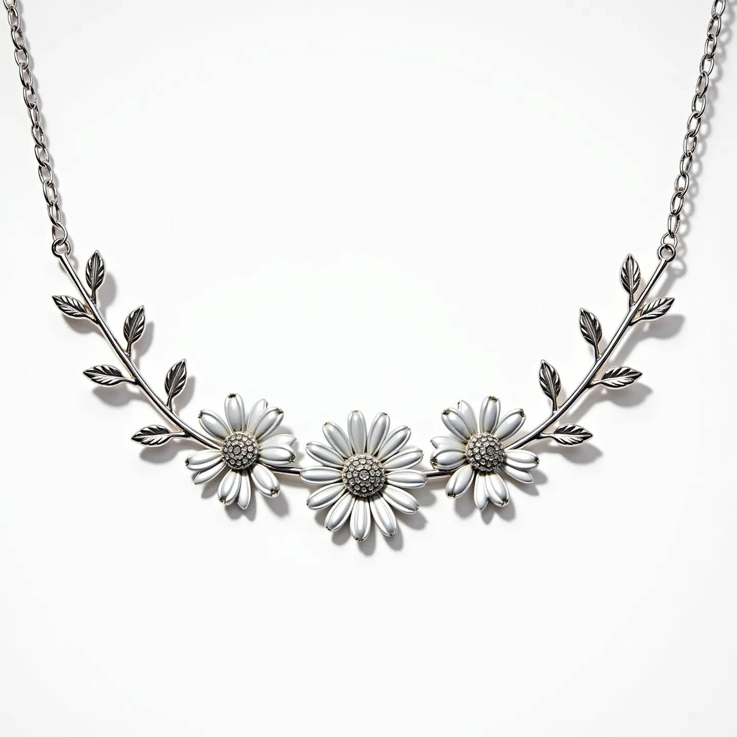 This daisy necklace features an elegant design with three prominent daisy motifs, each crafted with petals resembling silver-toned metal, lending a sleek and polished look. The centers of the daisies display intricate detailing, possibly using small textured metal pieces to mimic the natural texture of real daisy centers. The daisies are connected by a branch-like structure with leaf details, all rendered in a matching metallic finish, adding a graceful and organic aspect to the design. The necklace is completed with a simple chain that appears to be made of the same metal material, providing a cohesive aesthetic. It is likely secured with a standard metal clasp, ensuring a seamless and secure closure.