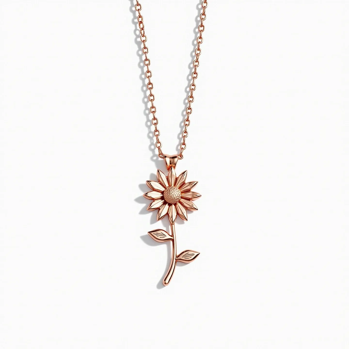 This daisy necklace is crafted from a shiny rose gold-toned metal, featuring a pendant shaped like a daisy with meticulously detailed petals and a textured center. The pendant includes a stem and leaves, enhancing its floral design. It is suspended from a classic chain with elliptical links, which adds a touch of elegance and continuity to the piece. The necklace is likely to be secured by a standard clasp, ensuring ease of wear. The simplicity and elegance of this design highlight the beauty of the daisy motif prominently.