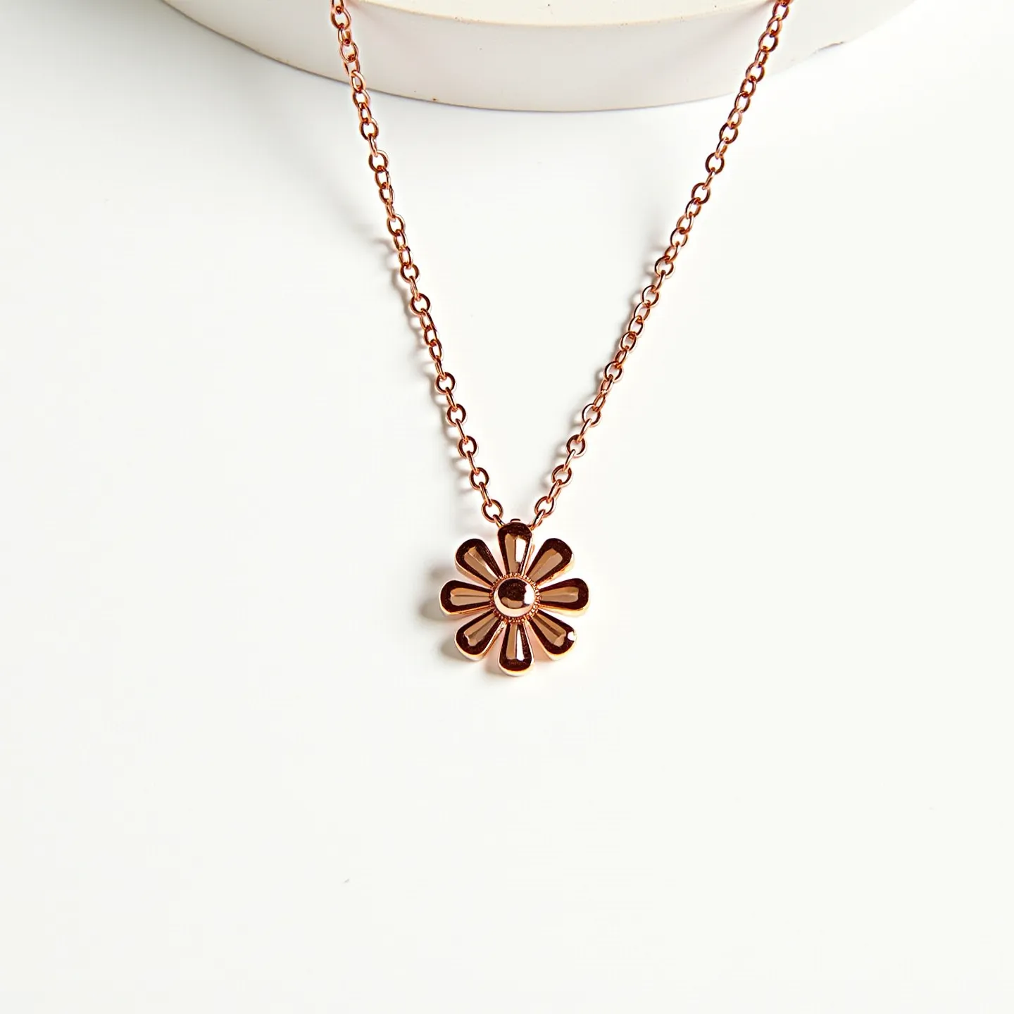 This daisy necklace features a delicate metal pendant shaped like a daisy, with a shiny finish that suggests a gold or bronze plating. The daisy’s petals are symmetrically arranged around a central circular element, which could potentially feature a gem or enamel for added detail, though specific gem characteristics are not clearly defined. The pendant is suspended from a fine chain, likely crafted from matching metal links to complement the pendant. The necklace includes a subtle clasp, which may be a standard spring ring or lobster clasp, ensuring secure attachment and ease of wear.