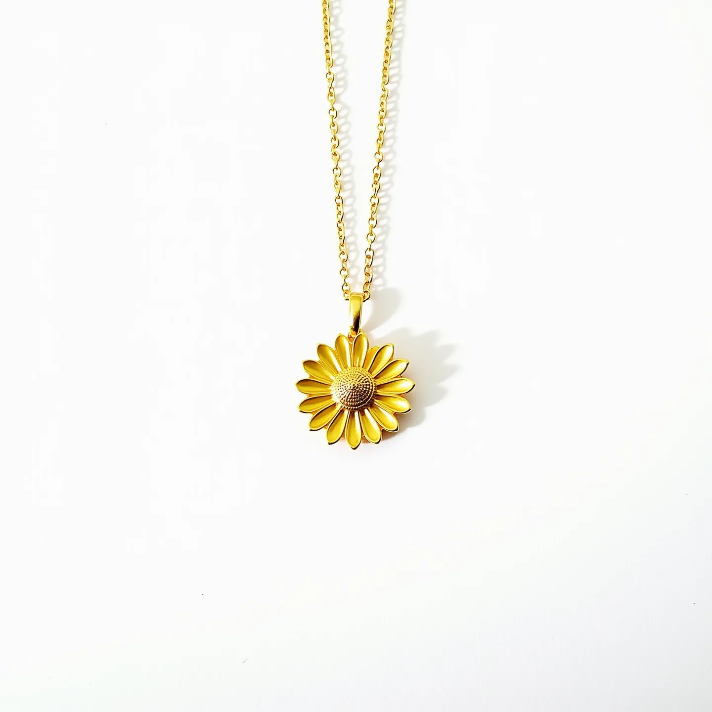 This daisy necklace features a delicate design with a central daisy pendant crafted in a gold tone, highlighting its petals with meticulous attention to detail. The chain appears to be a medium gauge cable, also in a gold tone, which complements the pendant. The daisy center has a textured surface, adding a touch of elegance and interest to the piece. The pendant is attached via a small bail that connects seamlessly to the chain, ensuring stability in wear. The simplicity of the necklace’s design emphasizes the charm and grace often associated with floral motifs.