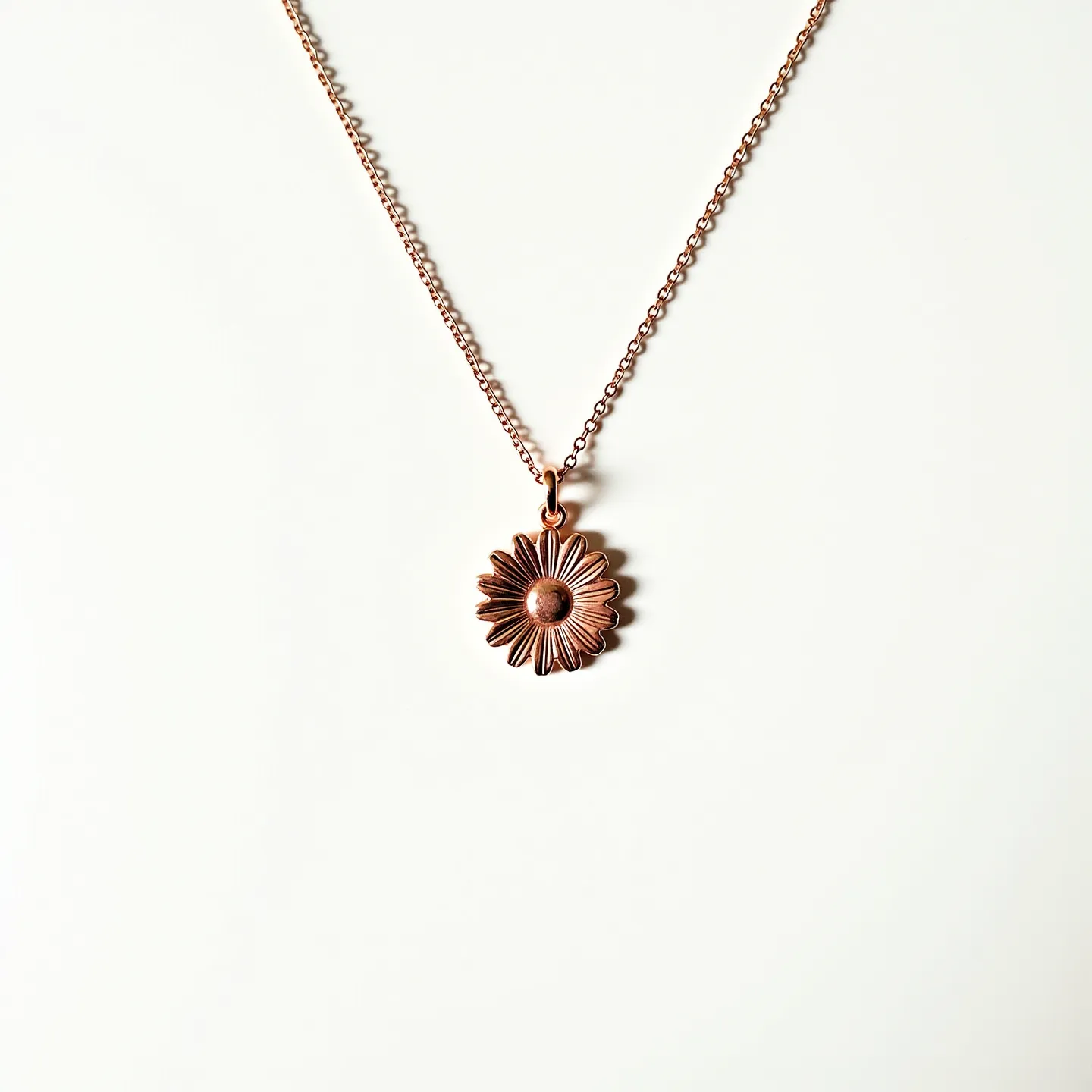 This daisy necklace features a delicate pendant shaped like a daisy, crafted from a copper-colored metal that gives it a rustic and vintage appeal. The pendant's petals are detailed, and the center is raised, accentuating the floral design without the presence of any gemstones. It hangs from a simple link chain that matches the pendant's color, likely made of the same metal, contributing to a cohesive look. The necklace is equipped with a standard lobster clasp, ensuring secure attachment and ease of wear.