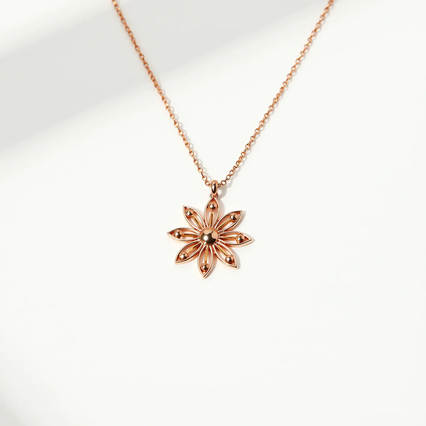 This daisy necklace features a finely crafted pendant in the shape of a daisy, made from a polished metal with a gold-tone finish. The petals of the daisy are elongated and gracefully arranged around a central sphere, creating an elegant and delicate appearance. Small, rounded embellishments are symmetrically placed on each petal, enhancing the intricate design. The chain appears to be a simple cable style, complementing the pendant’s design. The necklace is completed with a small bail attaching the pendant to the chain, providing a seamless connection.