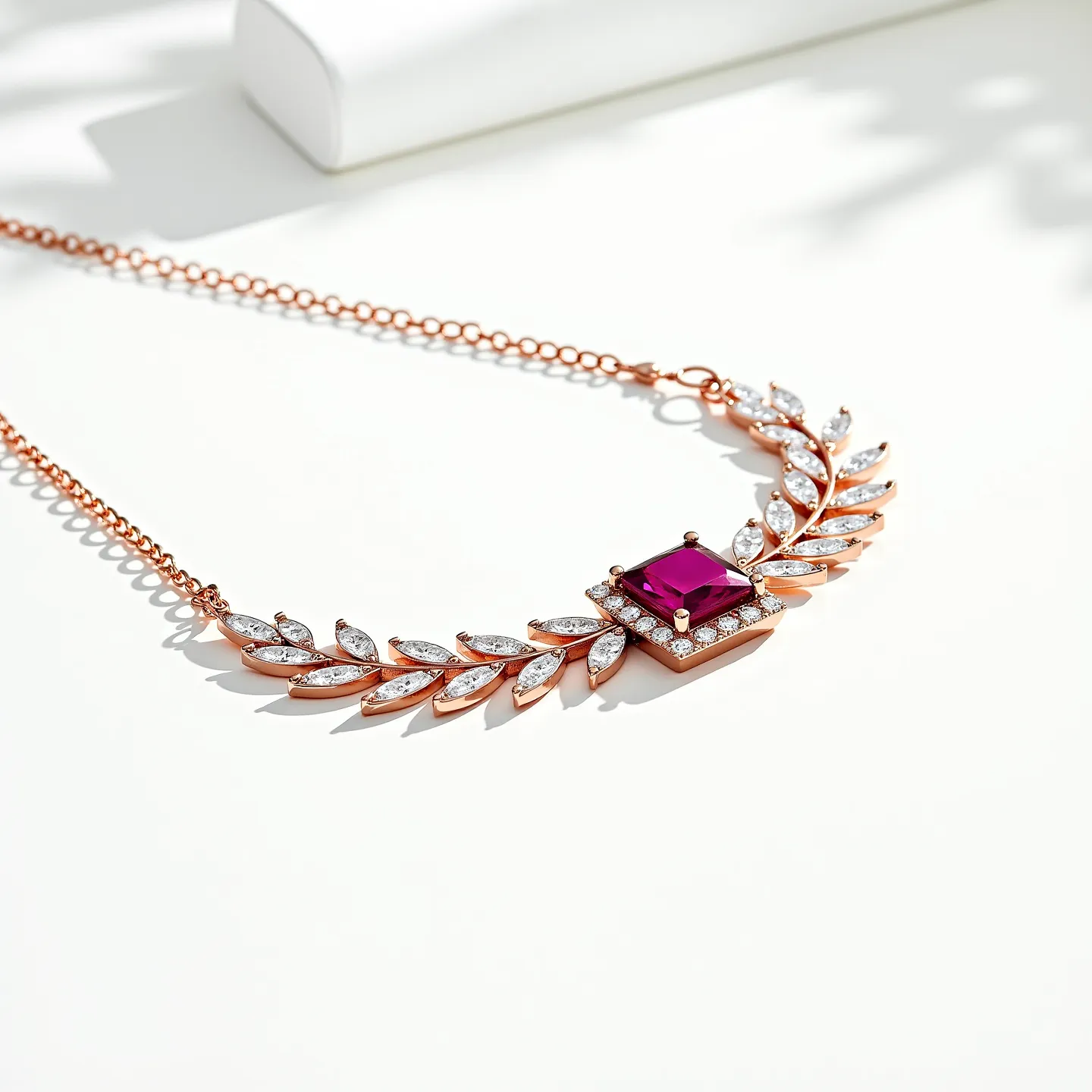 This diamond choker necklace features a luxurious design with a central square-cut ruby gemstone set in prongs, surrounded by small, brilliant-cut diamonds arranged in a halo setting on a rose gold base. The necklace is composed of an intricate arrangement of marquise-shaped diamonds forming a leaf-like pattern, accentuating the centerpiece. The diamonds are securely set in rose gold, which enhances their sparkle and complements the deep red hue of the ruby. The necklace is finished with a delicate rose gold chain and a secure clasp for attachment, ensuring both elegance and functionality.