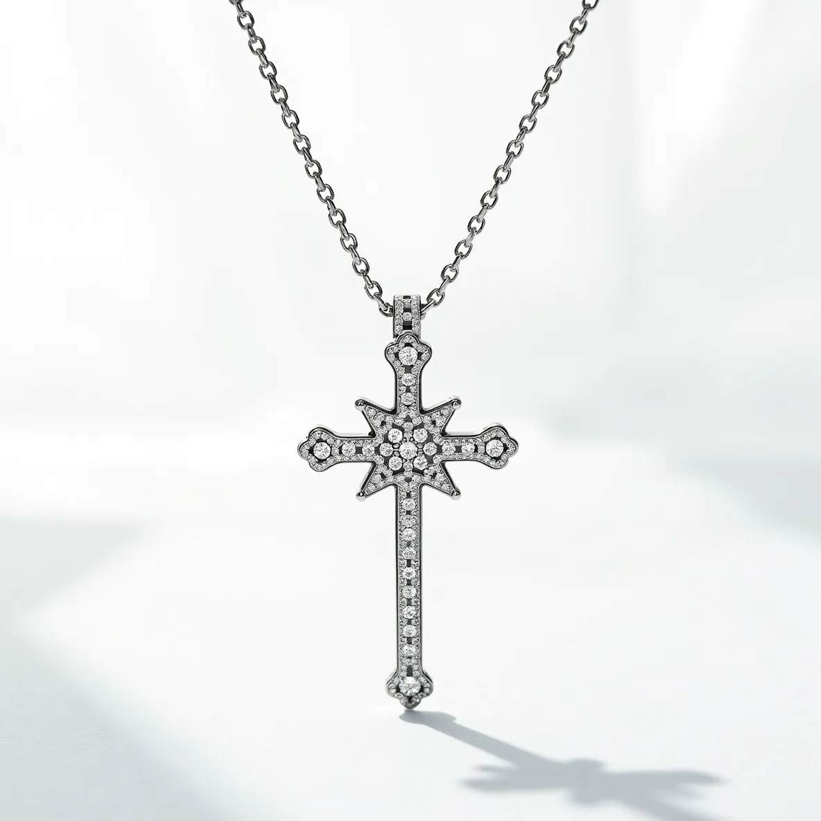 This diamond cross necklace showcases a striking cross-shaped pendant adorned with numerous small, round-cut diamonds. The gems are set in a pavé style, covering the surface uniformly and accentuating the structured edges and the bold starburst center design. The metal appears to be a polished white gold or platinum, complementing the bright sparkle of the diamonds. The necklace is attached to a delicate yet sturdy chain that supports the pendant gracefully. A subtle loop bail connects the pendant to the chain seamlessly, contributing to the overall elegant and refined appearance of the piece.