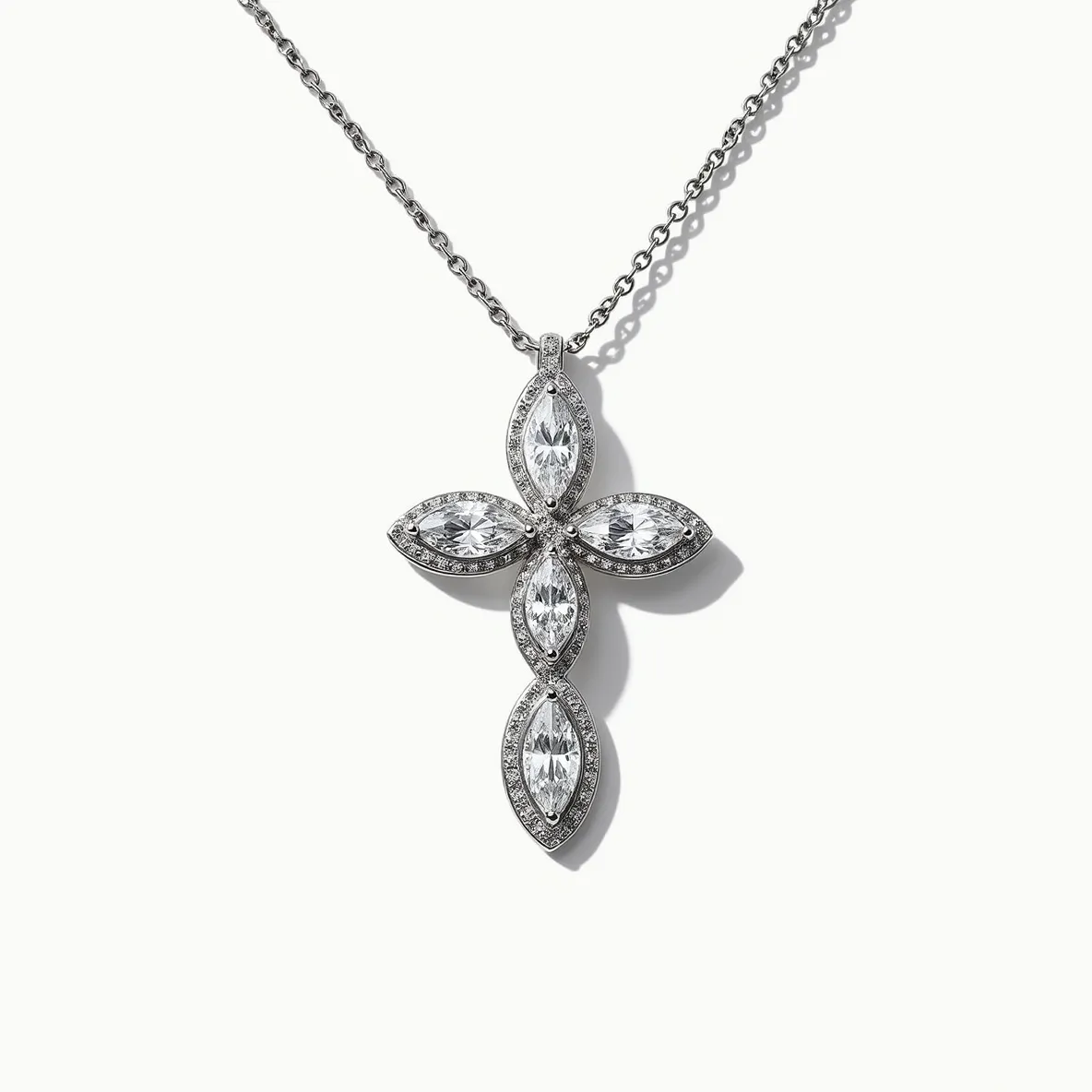 This diamond cross necklace features a striking design with four marquise-cut diamonds arranged to form the shape of a cross. The marquise diamonds are set in a halo setting, surrounded by smaller round diamonds that enhance their brilliance. The necklace is crafted from a polished metal, likely white gold or platinum, which complements the diamonds and adds to the elegance of the piece. The pendant is suspended from a delicate chain, providing a seamless and sophisticated attachment.