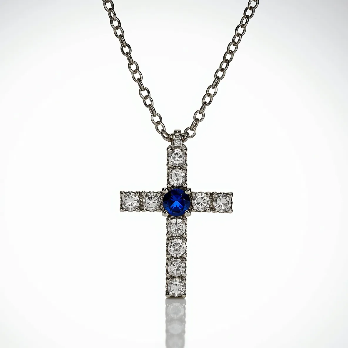 This diamond cross necklace features a striking design centered around a vibrant blue gemstone, likely a sapphire, placed prominently at the intersection of the cross. The cross itself is adorned with round-cut diamonds that are symmetrically set around the centerpiece, enhancing its brilliance and elegant appeal. The diamonds are secured in a classic prong setting, allowing light to pass through and amplify their sparkle. The necklace chain is composed of a polished metal, possibly white gold or platinum, which provides a sleek and modern contrast to the dazzling gems. The necklace is completed with a secure clasp, ensuring it stays in place when worn.