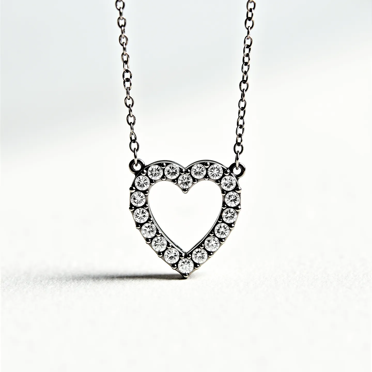 This diamond heart necklace features a delicate metal chain that supports a heart-shaped pendant encrusted with small, round diamonds. Each diamond is set in a classic prong setting, which enhances their brilliance and secures them firmly in place. The pendant is designed with an open-center heart, emphasizing the symmetrical arrangement of the stones around its outline. The chain appears to connect directly to the heart pendant through two small loops attached to its sides, providing a seamless and elegant appearance. The choice of materials and craftsmanship highlights the necklace's simplicity and sophistication.