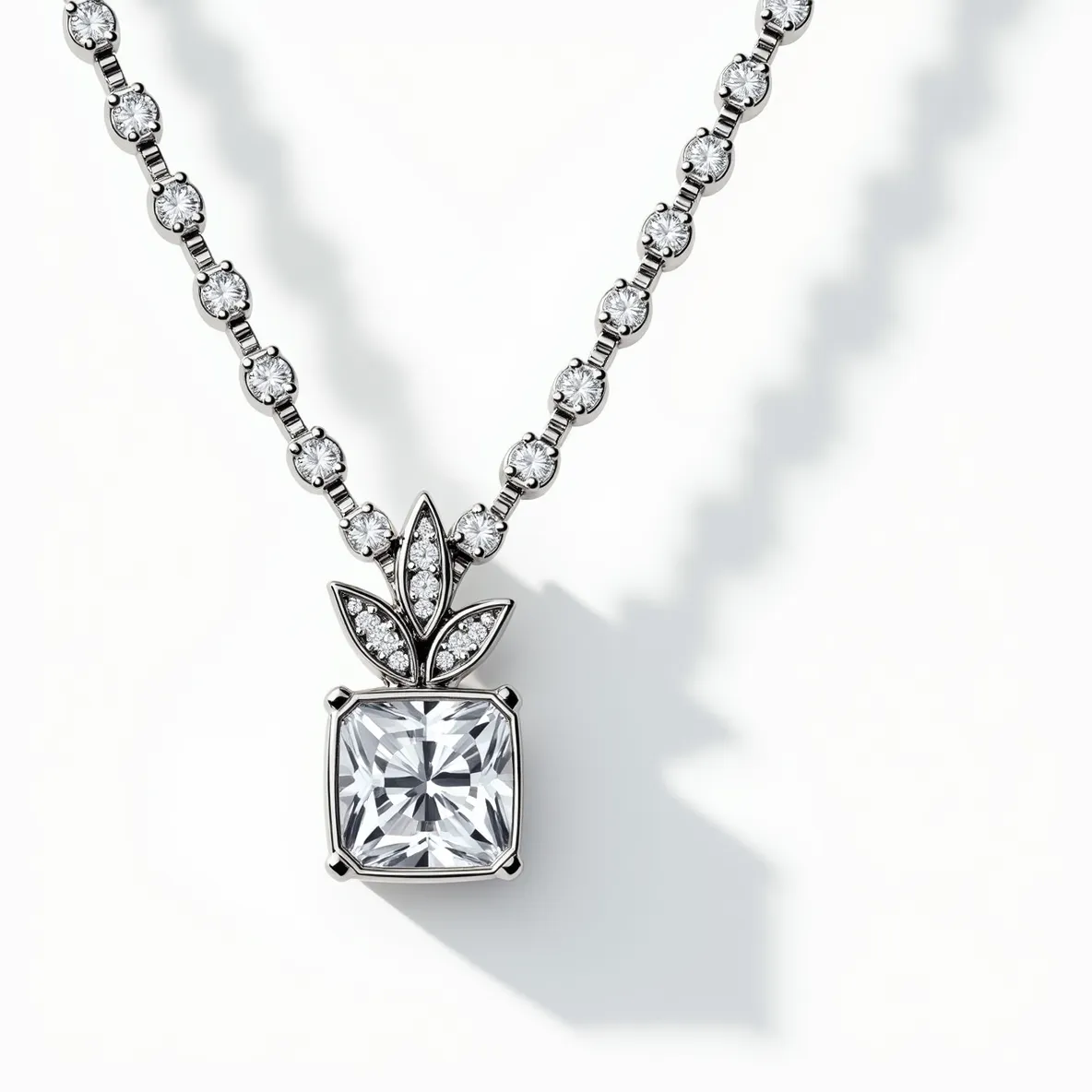 This diamond necklace features a striking design with a central focus on a large, cushion-cut diamond set in a four-prong setting. Enhancing the central pendant are intricately placed smaller round diamonds, forming a floral motif above the main stone, providing elegance and a touch of nature-inspired aesthetics. The necklace chain itself is adorned with uniformly sized round diamonds, each set in bezel settings, which contribute to the overall sparkle and luxury of the piece. The immaculate craftsmanship is evident in the attention to detail and seamless integration of the stones throughout the necklace.