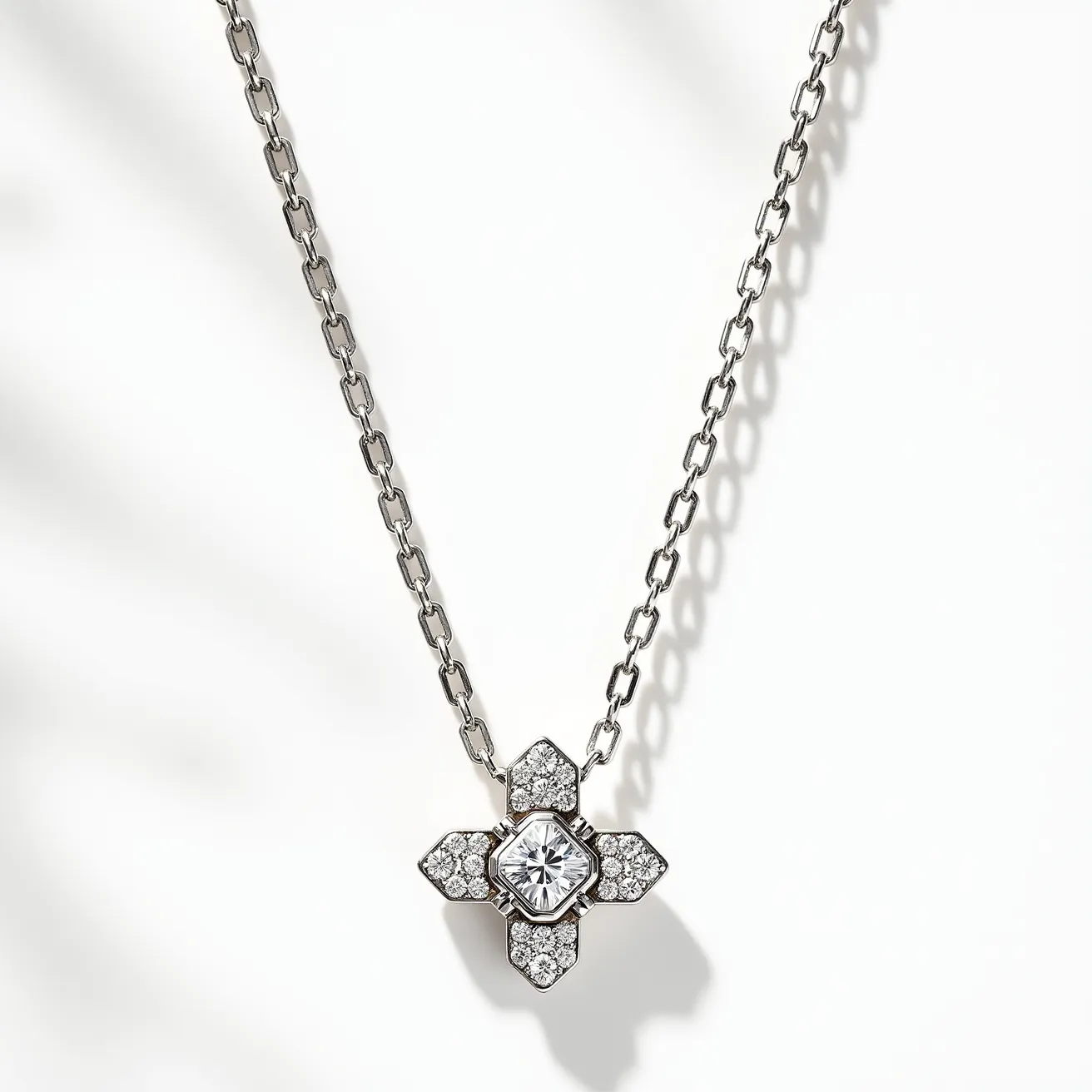 This diamond necklace features a central square-cut diamond set in a prong setting, surrounded by smaller round diamonds arranged in a floral pattern. The main diamond is prominently displayed at the center, with each petal-like extension containing multiple pavé-set diamonds, creating an accentuated sparkle. The pendant is attached to a chain with elongated links, likely made from a white gold or platinum material that complements the brilliance of the diamonds. The chain appears to have a simple clasp, aligning with the necklace's elegant and sophisticated design.