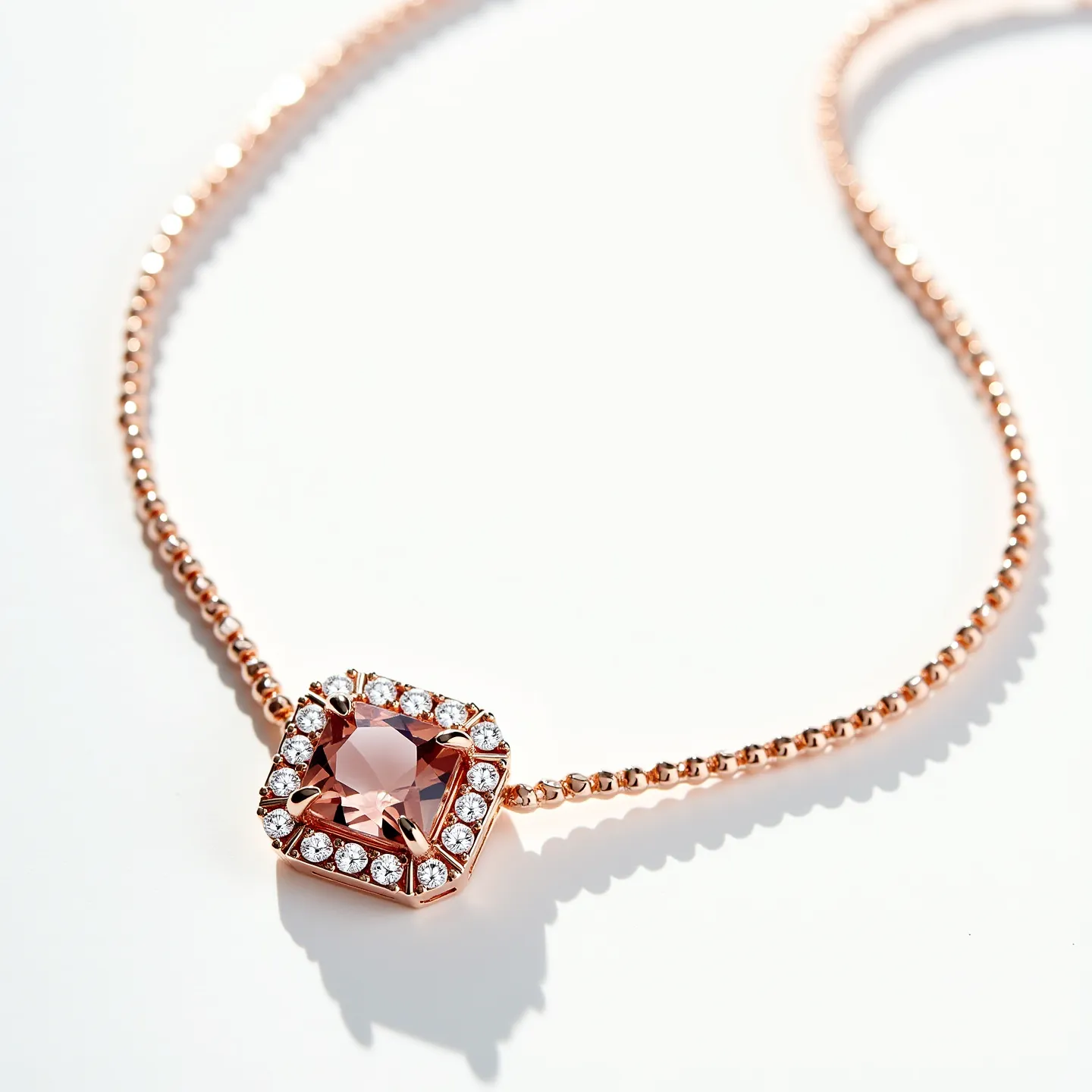 This diamond tennis necklace features a prominent pink stone, likely a pink sapphire or a similar gem, cut into a round shape and set in a sleek bezel setting. Surrounding this central stone is a halo of small, brilliant-cut diamonds that enhance its brilliance, each secured in a prong setting. The necklace is crafted from rose gold, as indicated by its warm hue, and consists of a series of small, interconnected links that create a smooth and flexible chain. The clasp is neatly integrated, ensuring a secure fit while maintaining the necklace’s elegant design.