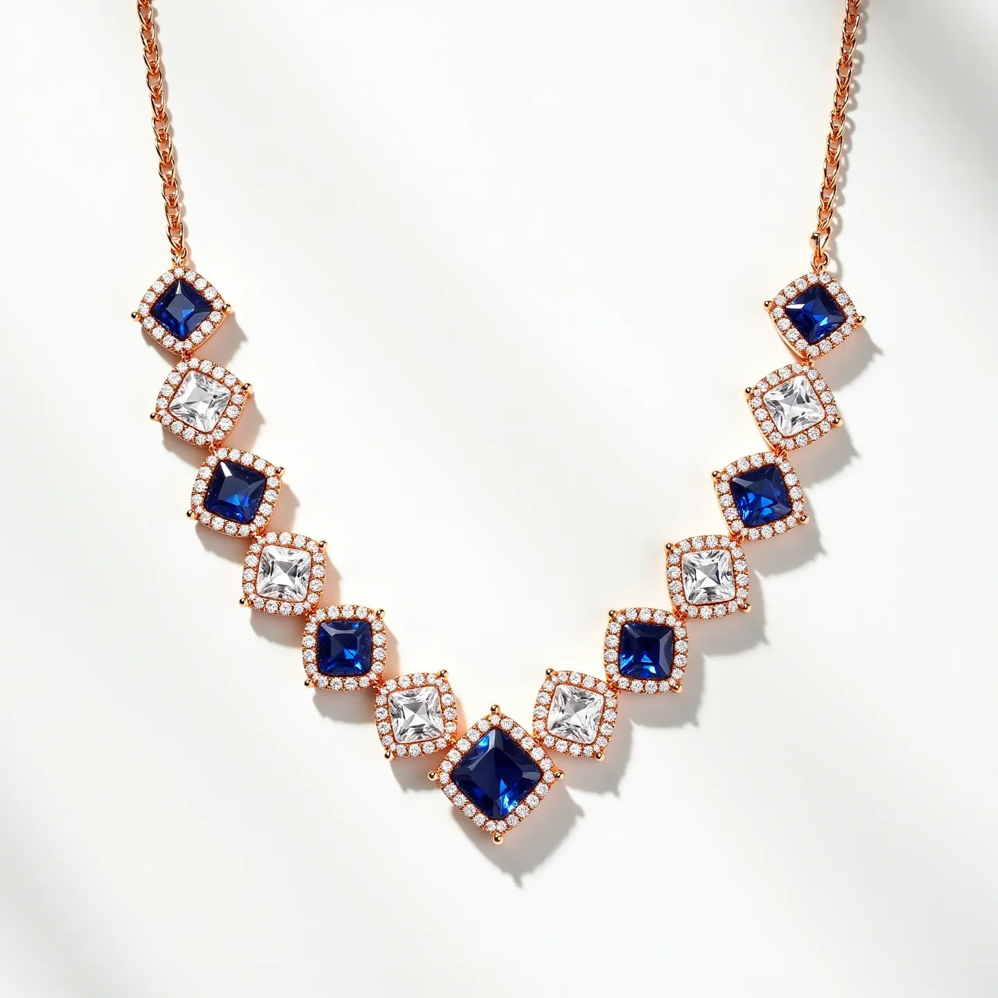 This diamond tennis necklace features a striking alternating pattern of deep blue square-cut gemstones, likely sapphires, and clear square-cut diamonds, both encased in a sophisticated rose gold setting. Each gem is bordered by a halo of smaller round diamonds, enhancing the overall brilliance and elegance. The necklace is linked with a rose gold chain, complementing the gemstone settings. The clasp or attachment style is discreet, maintaining the necklace's seamless design.