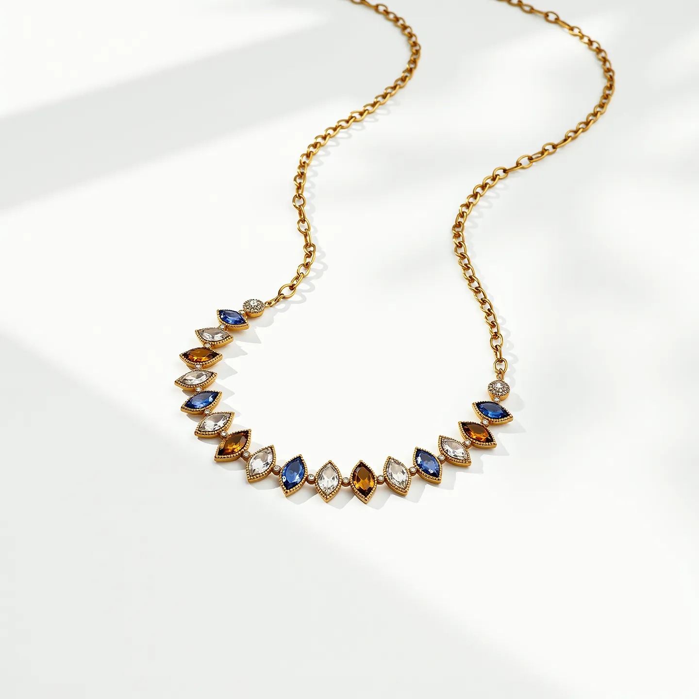 This diamond tennis necklace features an elegant combination of gold chain links and a series of marquise-cut gemstones set in yellow gold bezels. The necklace showcases alternating stones in varied colors, including rich blue sapphires, sparkling white diamonds, and deep amber stones, all in marquise settings that highlight their brilliance and color. The stones are meticulously set with a bezel setting, ensuring they are securely held while allowing them to catch light beautifully. A discrete clasp ensures the necklace sits elegantly around the neck, combining sophistication and secure wearing.