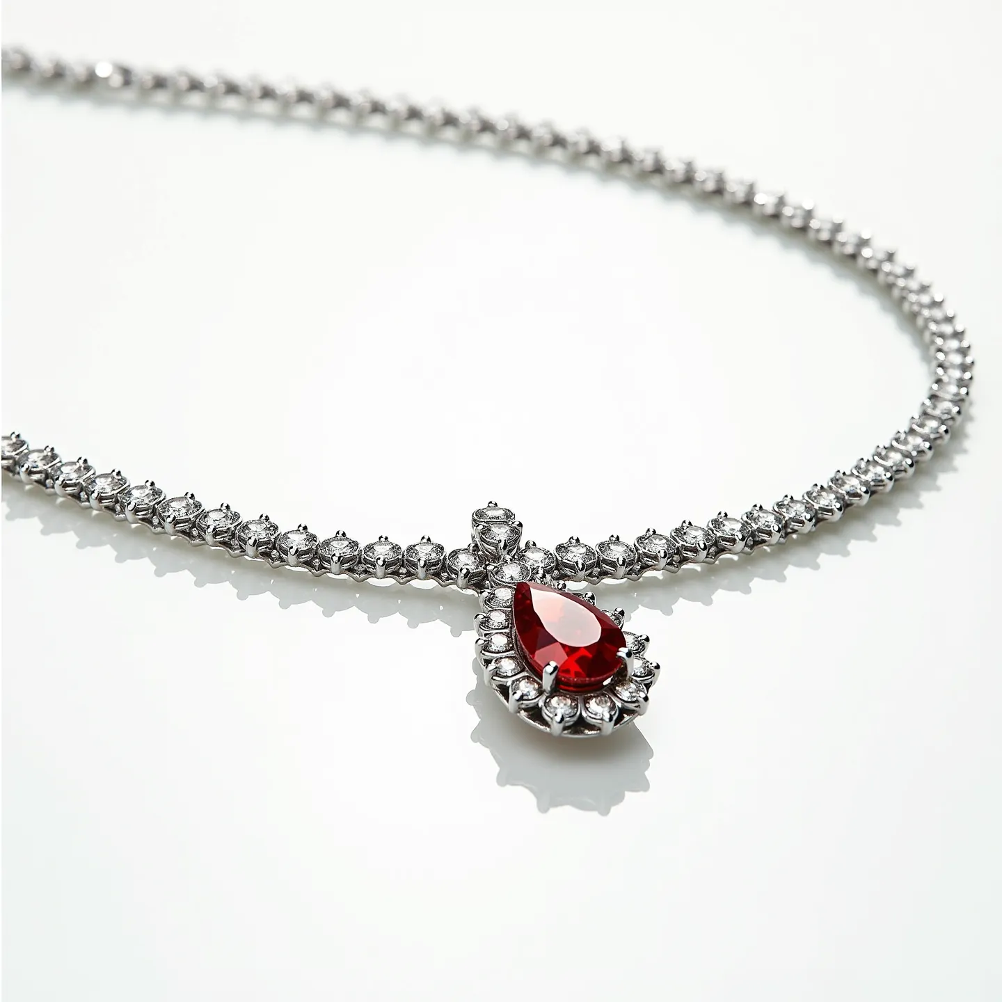 This diamond tennis necklace features a series of round-cut diamonds that are set in a continuous line, creating a classic and elegant design. The necklace includes a striking centerpiece, showcasing a vibrant pear-shaped red gemstone, likely a ruby or red sapphire, surrounded by a halo of smaller diamonds, enhancing its brilliance. The setting appears to be crafted from a high-polish metal, possibly white gold or platinum, which complements the sparkle of the stones. A secure clasp, likely a box or tongue-and-groove style, ensures the necklace stays fastened, offering both beauty and functionality.