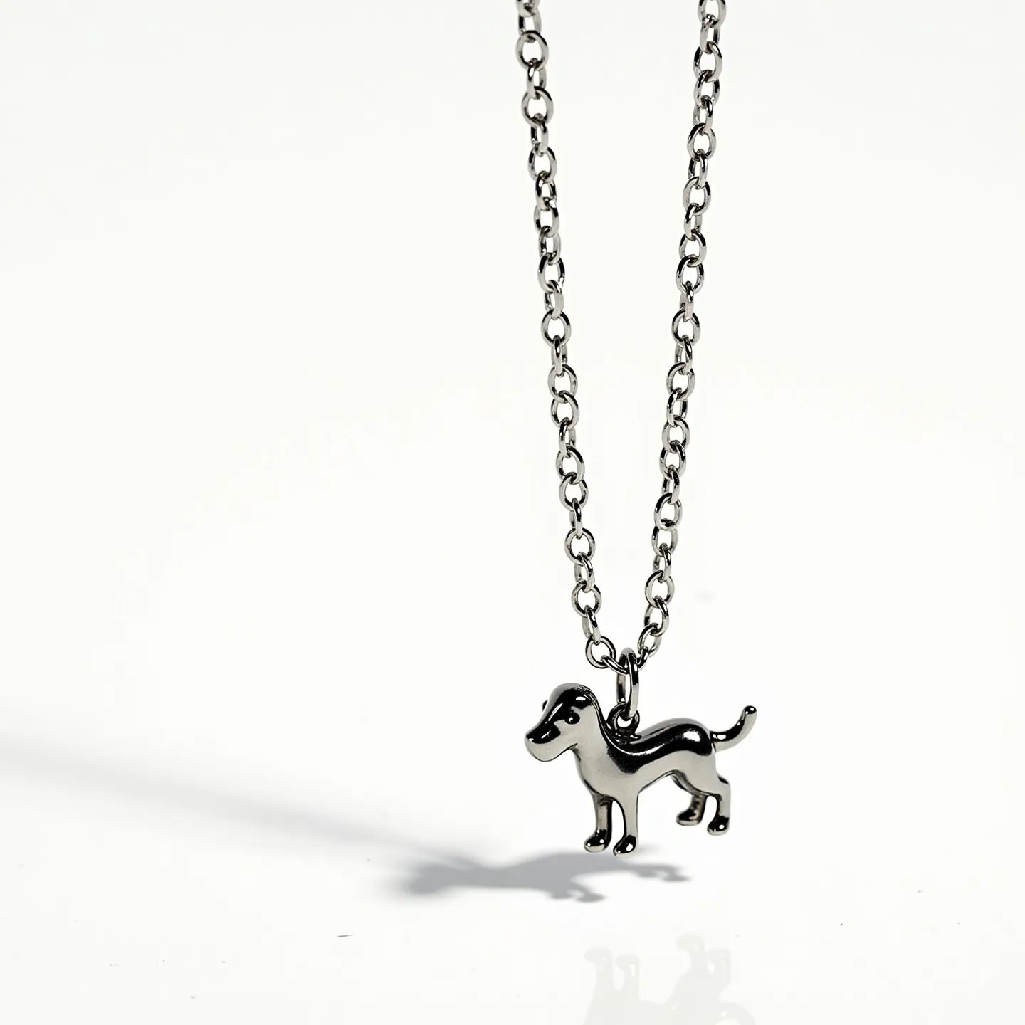 This dog necklace features a charming pendant in the shape of a dog, crafted from a polished metal, likely stainless steel or a similar shiny material. The chain links are medium-sized, providing a sturdy and stylish accompaniment to the pendant. The pendant showcases smooth, well-defined edges, emphasizing the dog's silhouette in a sleek design. There are no gemstones or embellishments adorning the pendant, focusing instead on the minimalist aesthetic of the piece. The necklace likely includes a typical clasp, such as a lobster claw or spring ring, for secure attachment.