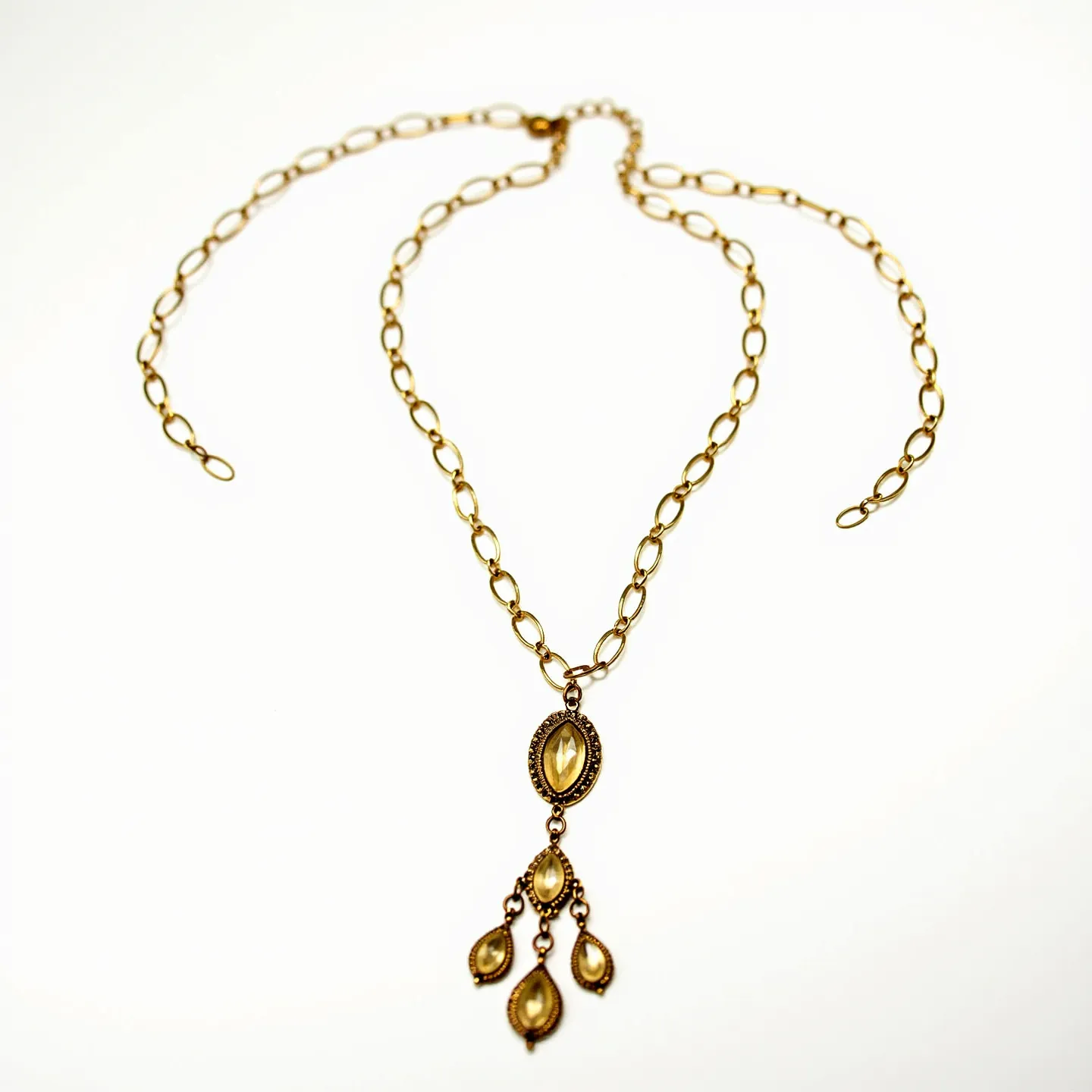 This drop necklace features an elegant design with a gold-toned chain composed of oval links that provide a classic and timeless appearance. The focal point of the necklace is a striking pendant adorned with four marquise-cut stones, which appear to be a warm yellow hue, possibly citrine or a similar gemstone. These stones are bezel set, enhancing their lustrous appeal while securely holding them in place. The pendant is designed with a cascading effect, where three smaller stones dangle delicately beneath a larger central stone, adding movement and sophistication to the piece. The necklace is equipped with a simple lobster clasp, ensuring ease of wear and security.