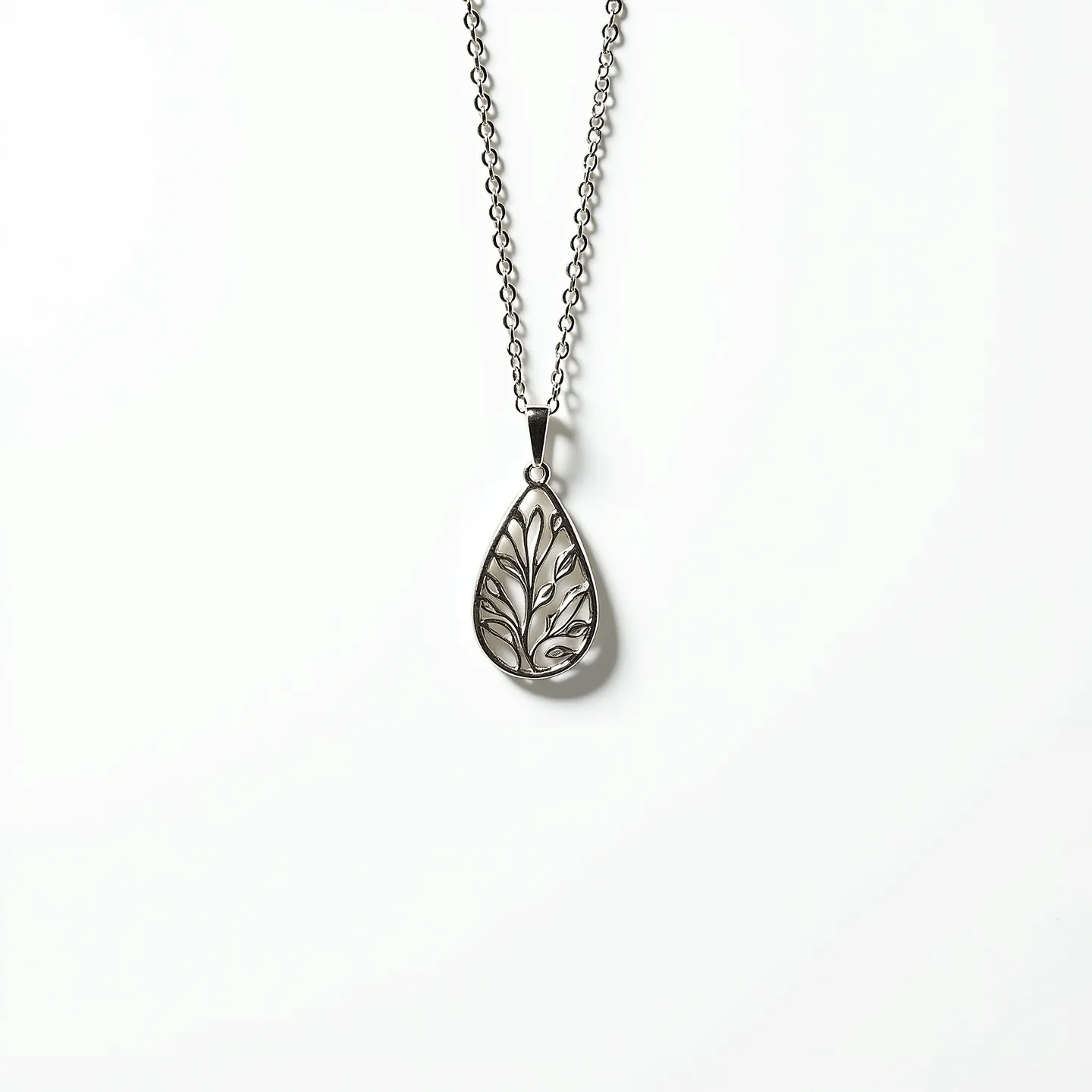 This drop necklace features a delicately crafted teardrop-shaped pendant, intricately designed with a leaf motif pattern. The pendant is made of a silver-toned metal, giving it a sleek and elegant appearance. It is suspended from a matching fine metal chain, which complements the pendant's design. The necklace is fastened with a simple loop and bail attachment that allows the pendant to dangle freely, adding to its graceful aesthetic. The overall design emphasizes a natural theme, highlighted by the artistic leaf patterns within the pendant.