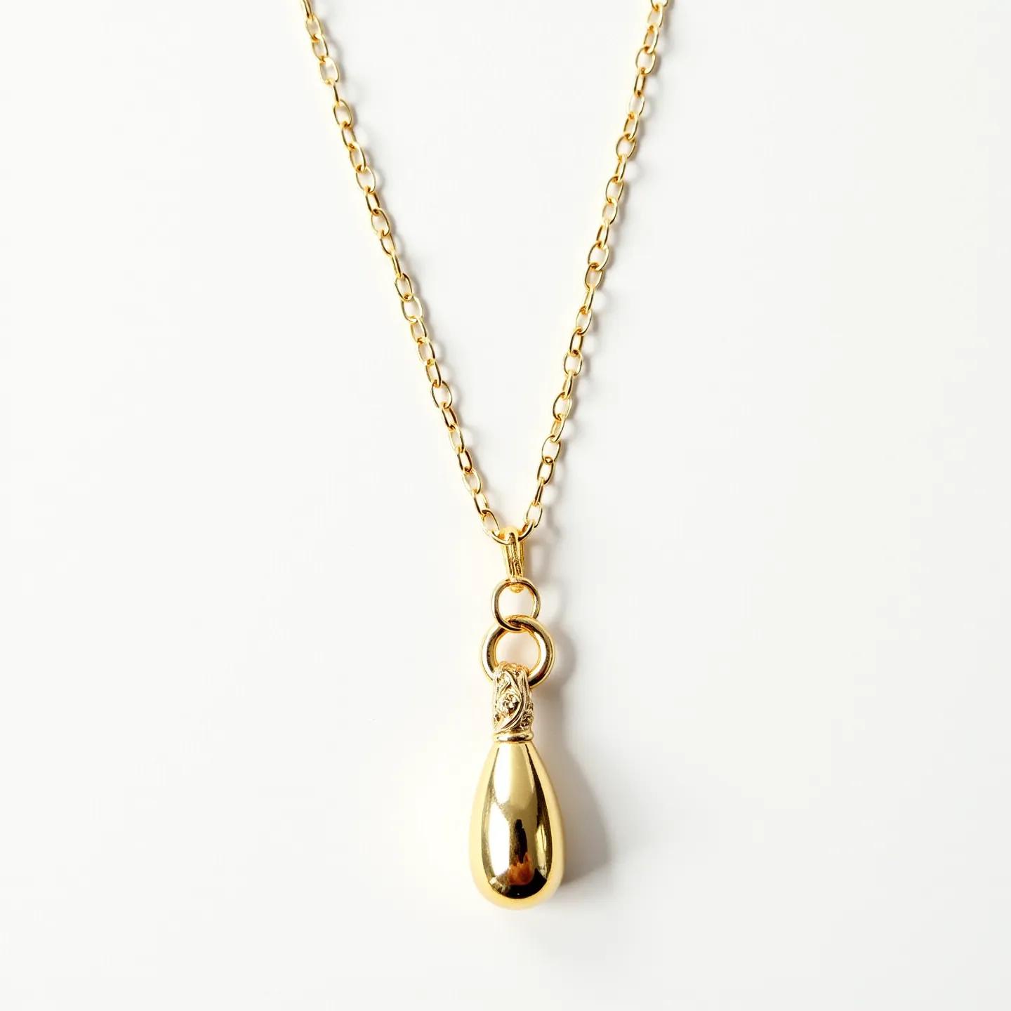 This drop necklace features a delicate, gold-toned chain with rounded links that connect to an elegantly crafted drop pendant. The pendant has a polished, smooth surface and resembles a teardrop shape, enhancing its shiny, reflective quality. It is attached to the chain with a refined interlocking loop mechanism, ensuring a secure connection. The absence of visible gems or stones keeps the design minimalistic yet sophisticated, highlighting the metallic luster of the gold tone. The necklace is likely fastened with a customary clasp, common in such designs, which provides ease of wear.