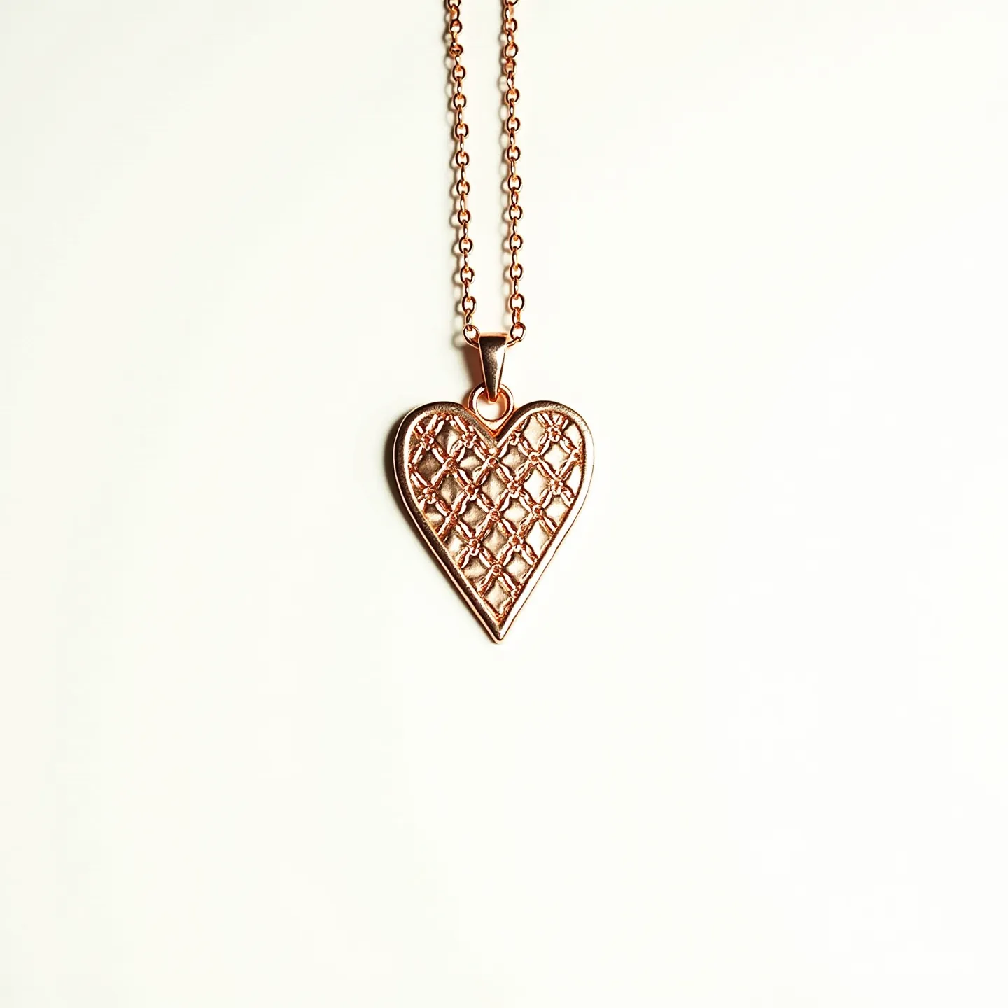 This engraved heart necklace features a pendant crafted from a polished, gold-toned metal, intricately designed with a lattice pattern. The pendant hangs from a delicate, matching metal chain, linked by a simple yet elegant bail. No additional gemstones or embellishments are present, allowing the detailed engraving to stand out as the primary decorative element. The necklace is secured with a classic lobster clasp, providing both practicality and ease for wearing.