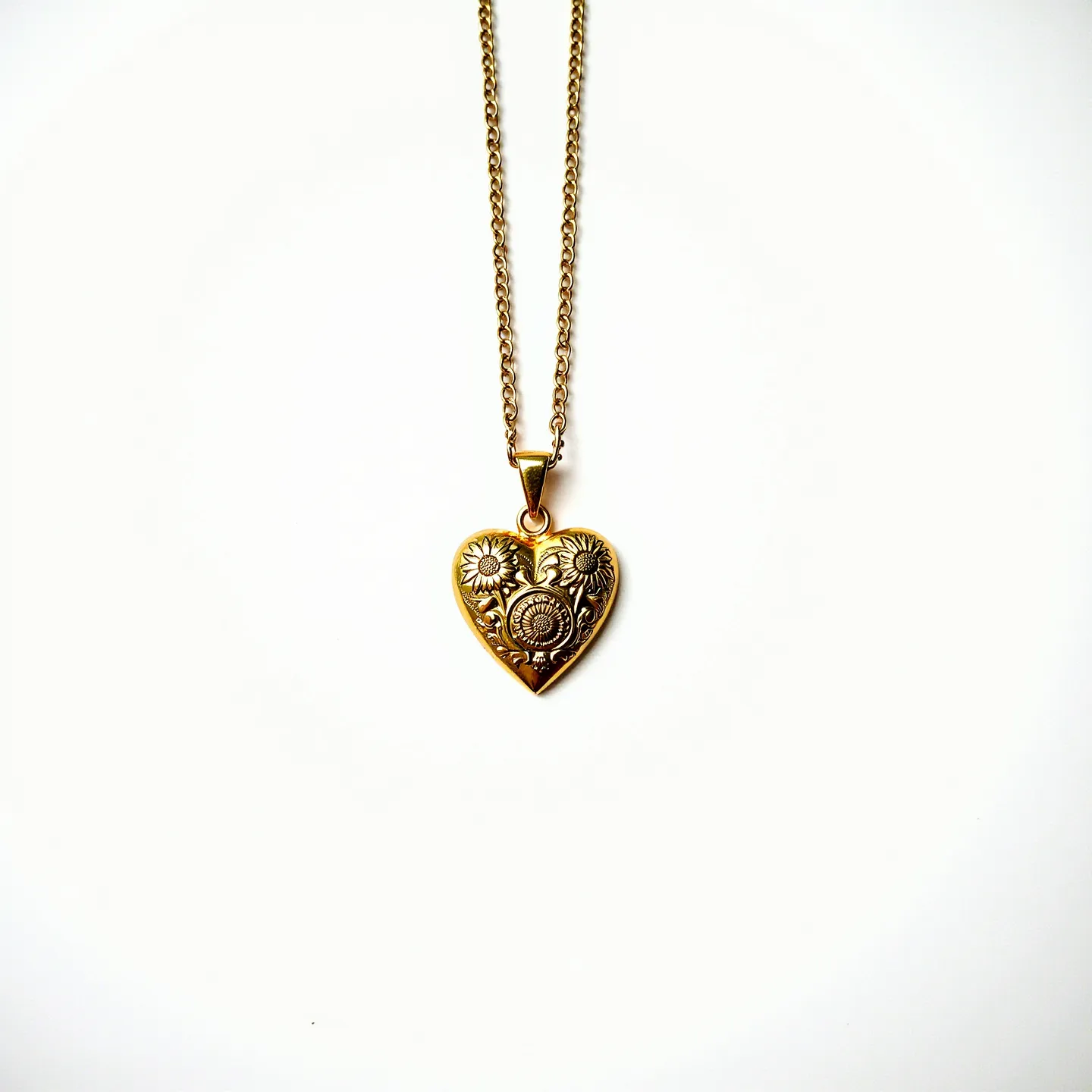 This engraved heart necklace features a pendant crafted from what appears to be gold, intricately detailed with floral motifs. The artistry of the engraving enhances its elegance, adding a textured design that showcases sunflowers and foliage. The pendant is suspended from a matching gold-toned chain, linked via a small, elegant bail. There are no visible gemstones, and the clasp of the necklace is not depicted in the image, suggesting it maintains a seamless aesthetic focus on the pendant itself.