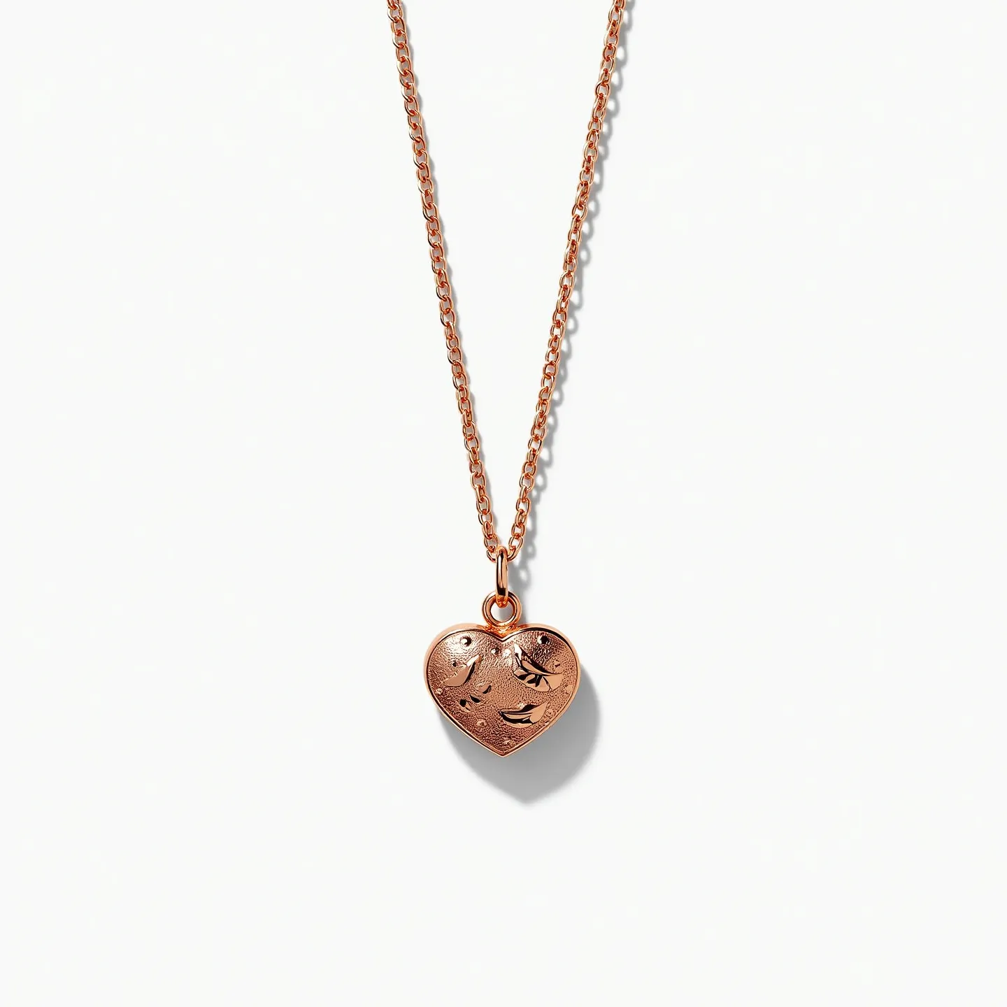 This engraved necklace features a heart-shaped pendant crafted from a warm, rose gold-toned metal, giving it a delicate and elegant appearance. The pendant showcases intricate engraved designs, adding depth and texture to its surface, with an organic motif that enhances its charm. It hangs from a fine chain that complements the pendant's hue and is equally refined in design. The necklace is secured with a standard lobster clasp, providing both functionality and ease of use. The simplicity and sophistication of the necklace make it a versatile accessory suitable for various occasions.