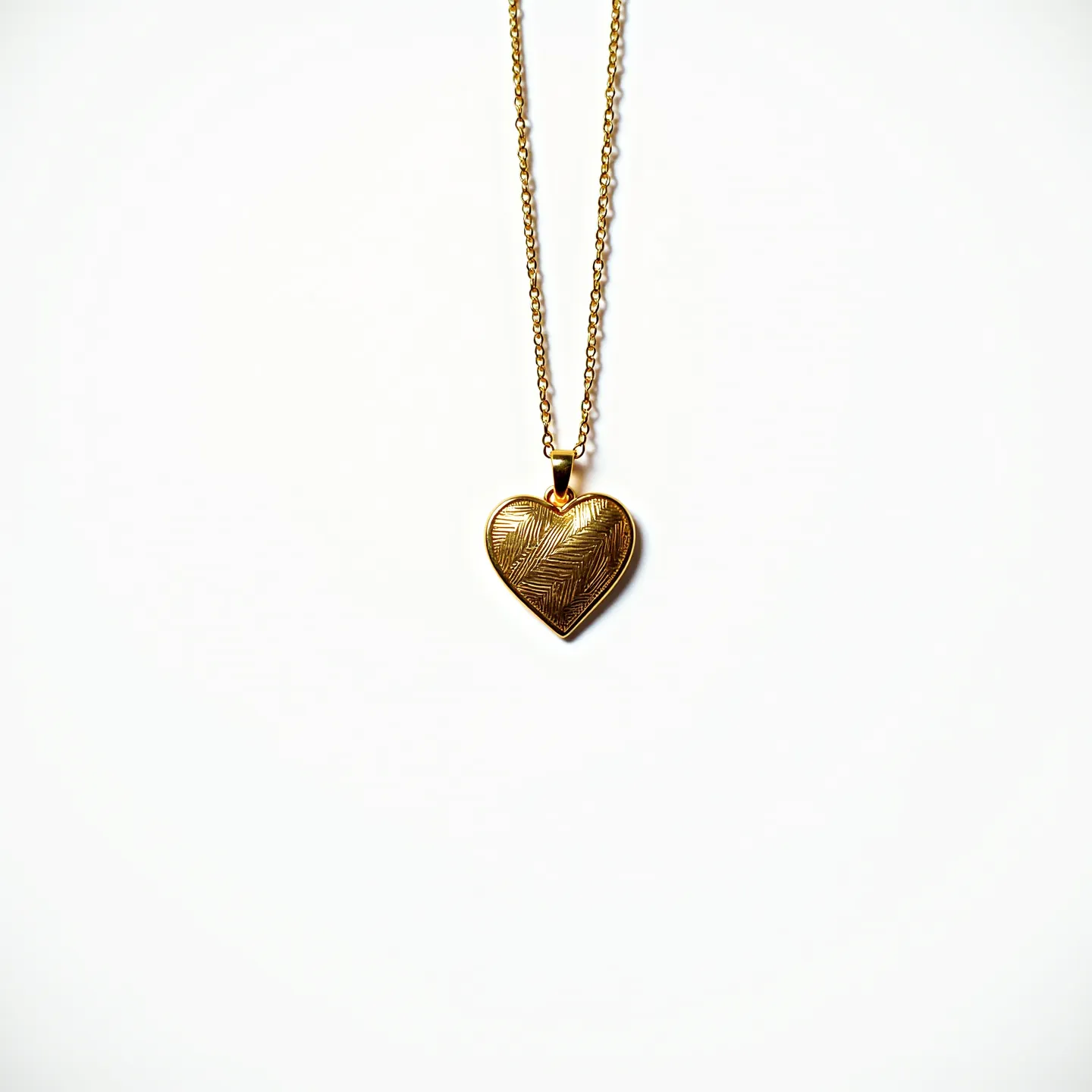 This engraved necklace features a heart-shaped pendant made of a gold-toned material, showcasing an intricately etched pattern that adds texture and visual interest. The pendant hangs from a delicate chain that is also gold-toned, complementing the overall aesthetic of the piece. The chain is designed with interconnected links, providing both durability and elegance. The necklace is fastened with a simple yet secure clasp, ensuring ease of wear while maintaining a classic and timeless appeal. The attention to detail in the engraving and the harmonious design of the pendant and chain make this necklace a standout accessory.