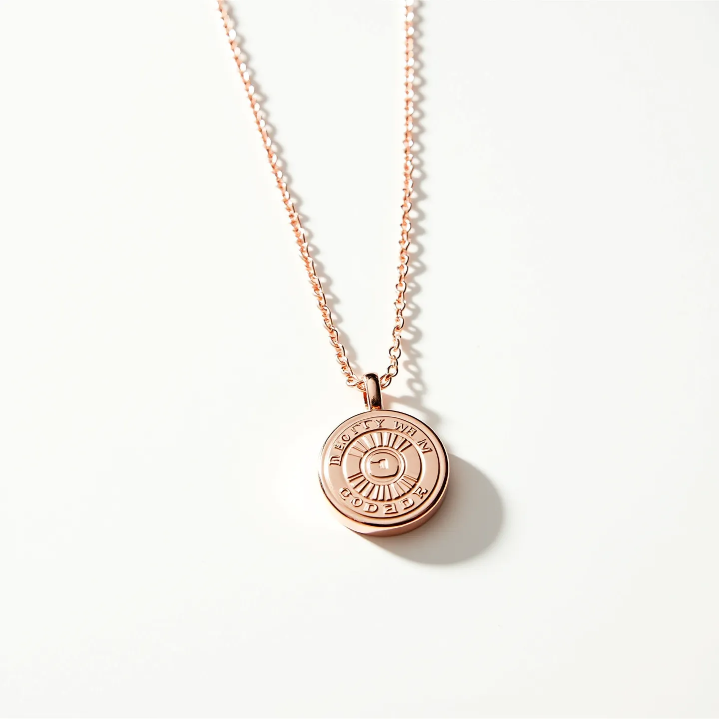 This engraved necklace features a circular pendant crafted from a metal with a rose gold finish, giving it a warm and elegant appearance. The pendant is attached to a delicate chain that likely matches the pendant's hue, creating a cohesive look. The pendant itself has detailed engravings that add a personalized touch, with text encircling a central design. The reverse side of the pendant remains simple, emphasizing the engravings on the front. The chain is connected to the pendant through a small, sturdy loop, providing secure attachment and ease of wear.